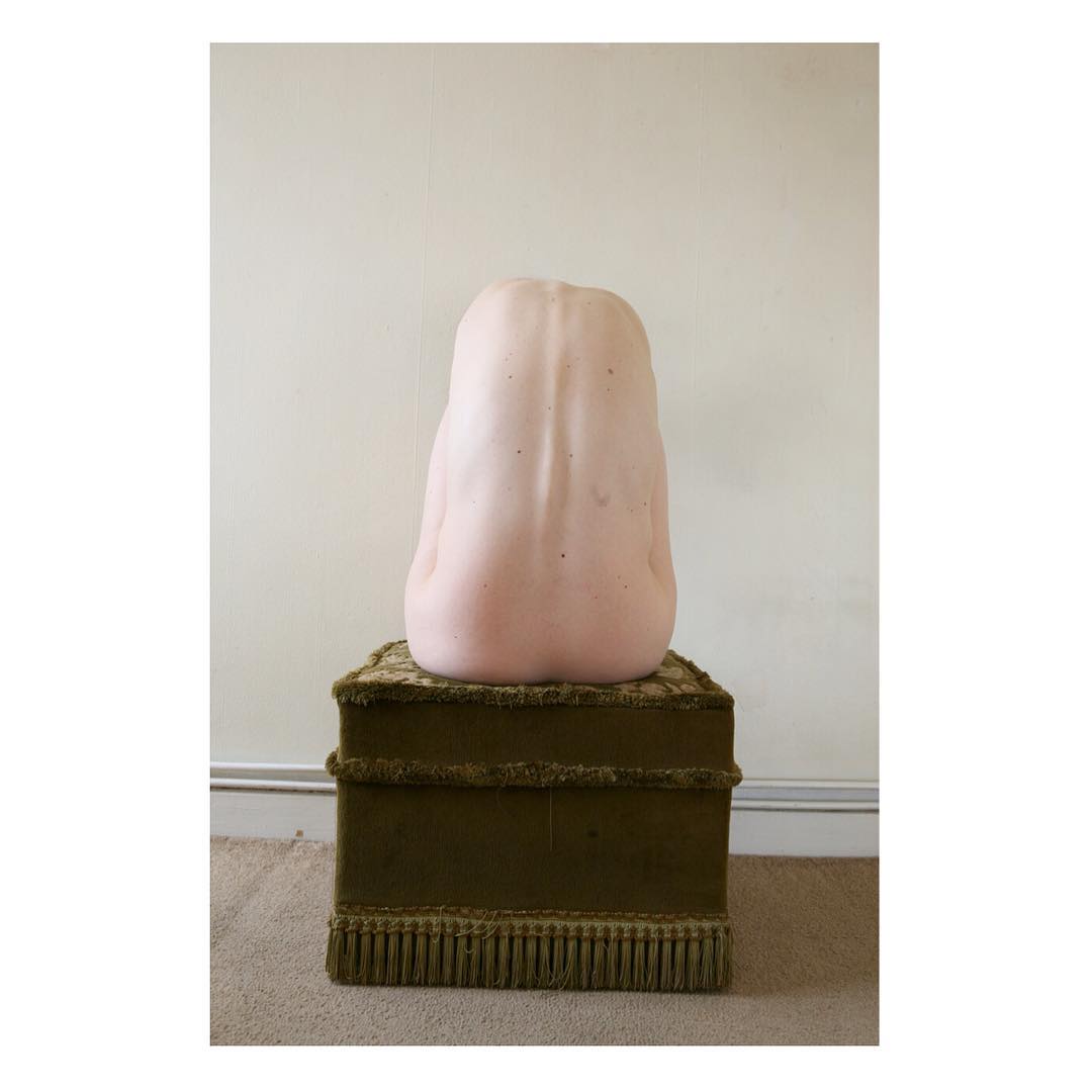 Selected works by Polly Penrose — A pale pink sculptural form with an organic, rounded silhouette sits atop a moss-green upholstered pedestal base.