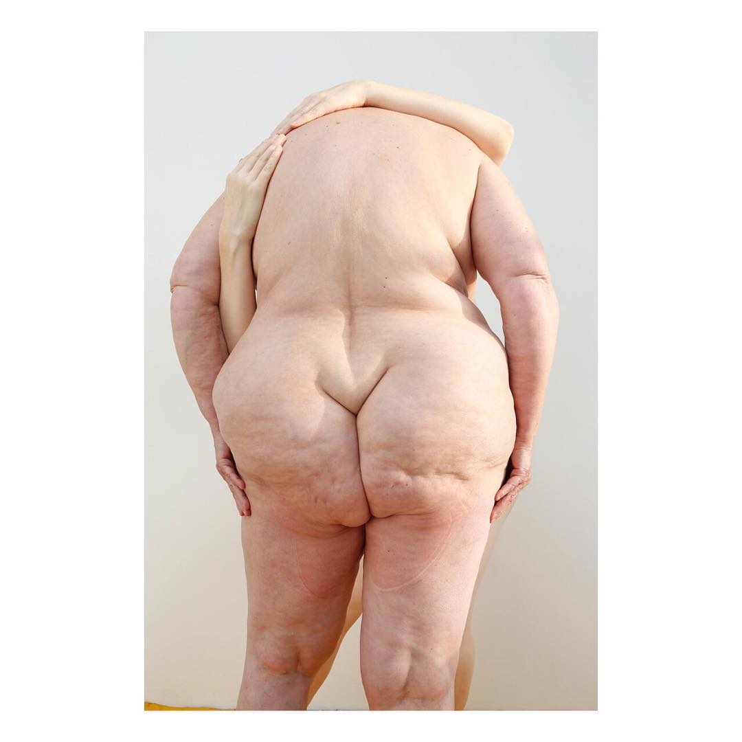 Selected works by Polly Penrose — Rear-view portrait photograph of a nude figure standing against a neutral grey background.