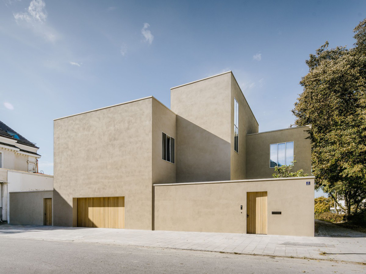Bogenhausen House by David Chipperfield Architects — The Bogenhausen House presents itself as a monolithic cream-rendered facade punctuated by oak-framed garage and entrance doors.