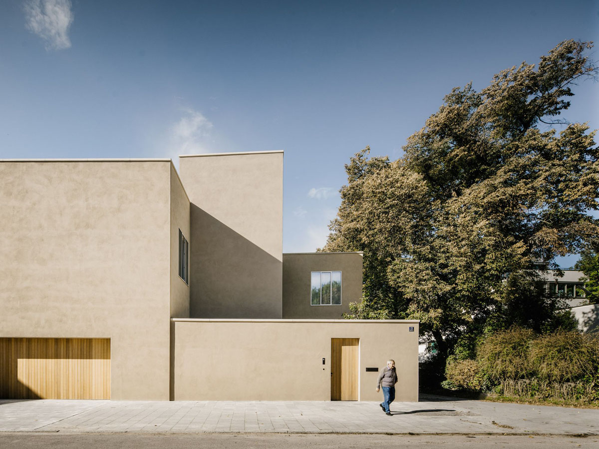 Bogenhausen House by David Chipperfield Architects — The Bogenhausen House presents its restrained street façade, a composition of sand-colored rendered planes interrupted by a single gridded window with dark...