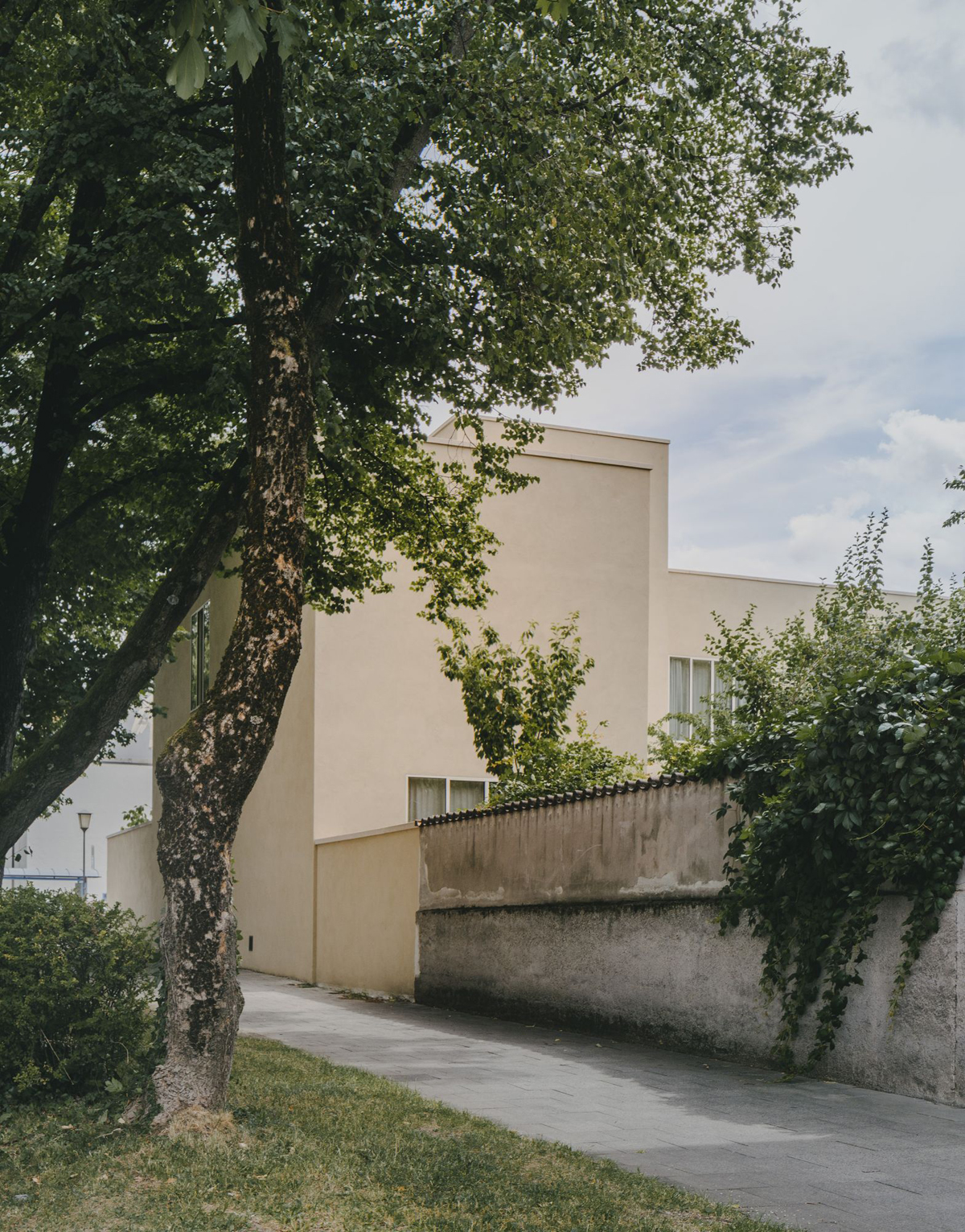 Bogenhausen House by David Chipperfield Architects — The Bogenhausen House presents itself to the street as a largely opaque composition: a cream-rendered facade punctuated by small fenestration, partially...
