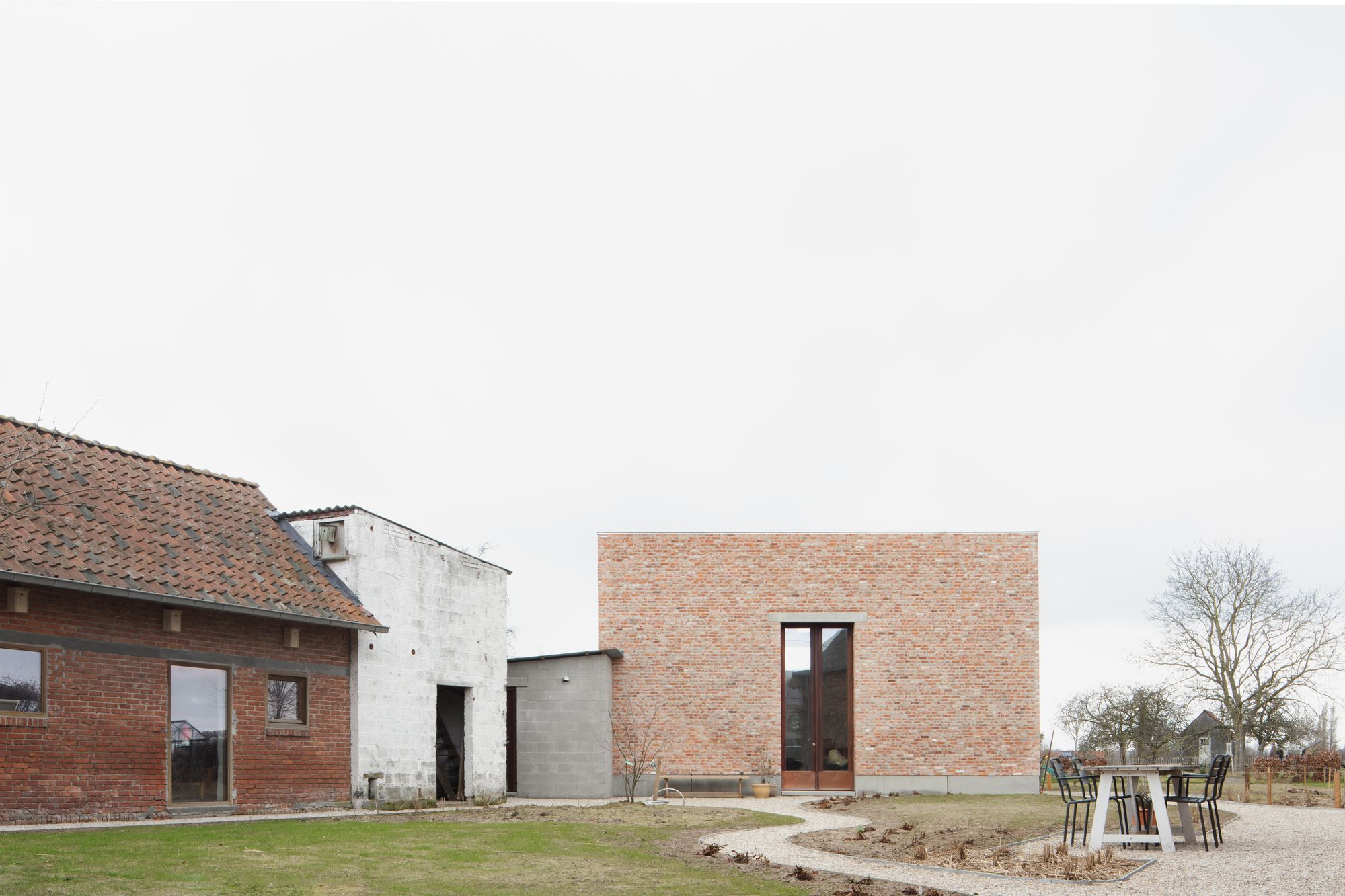 Studio SDS by GRAUX & BAEYENS — The newly constructed brick studio volume anchors the right side of the composition, its substantial double-height mass faced entirely in running-bond brick.