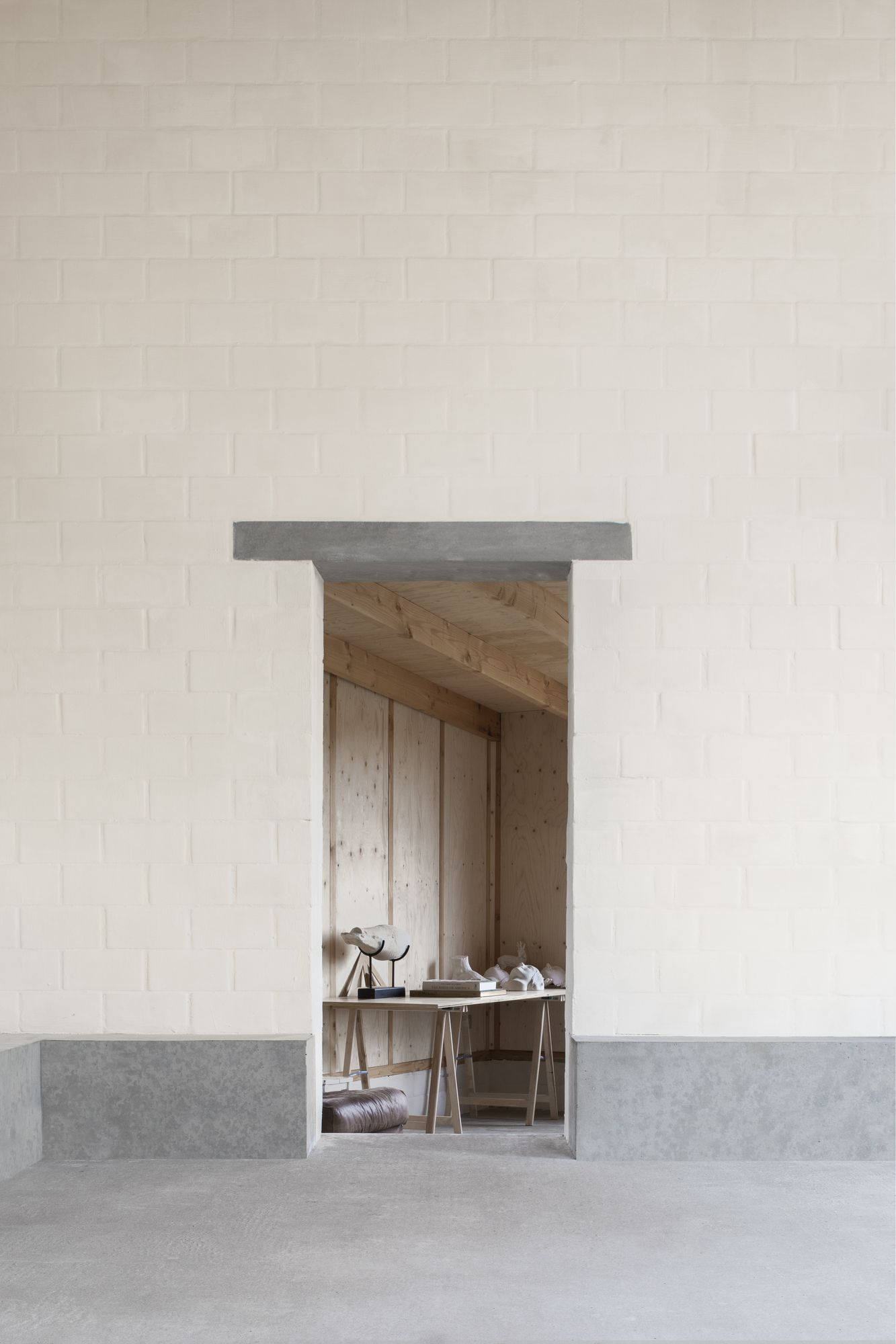 Studio SDS by GRAUX & BAEYENS — A recessed studio entrance framed by white brick walls in running bond pattern, with a deep grey concrete lintel and sill creating pronounced shadow lines.