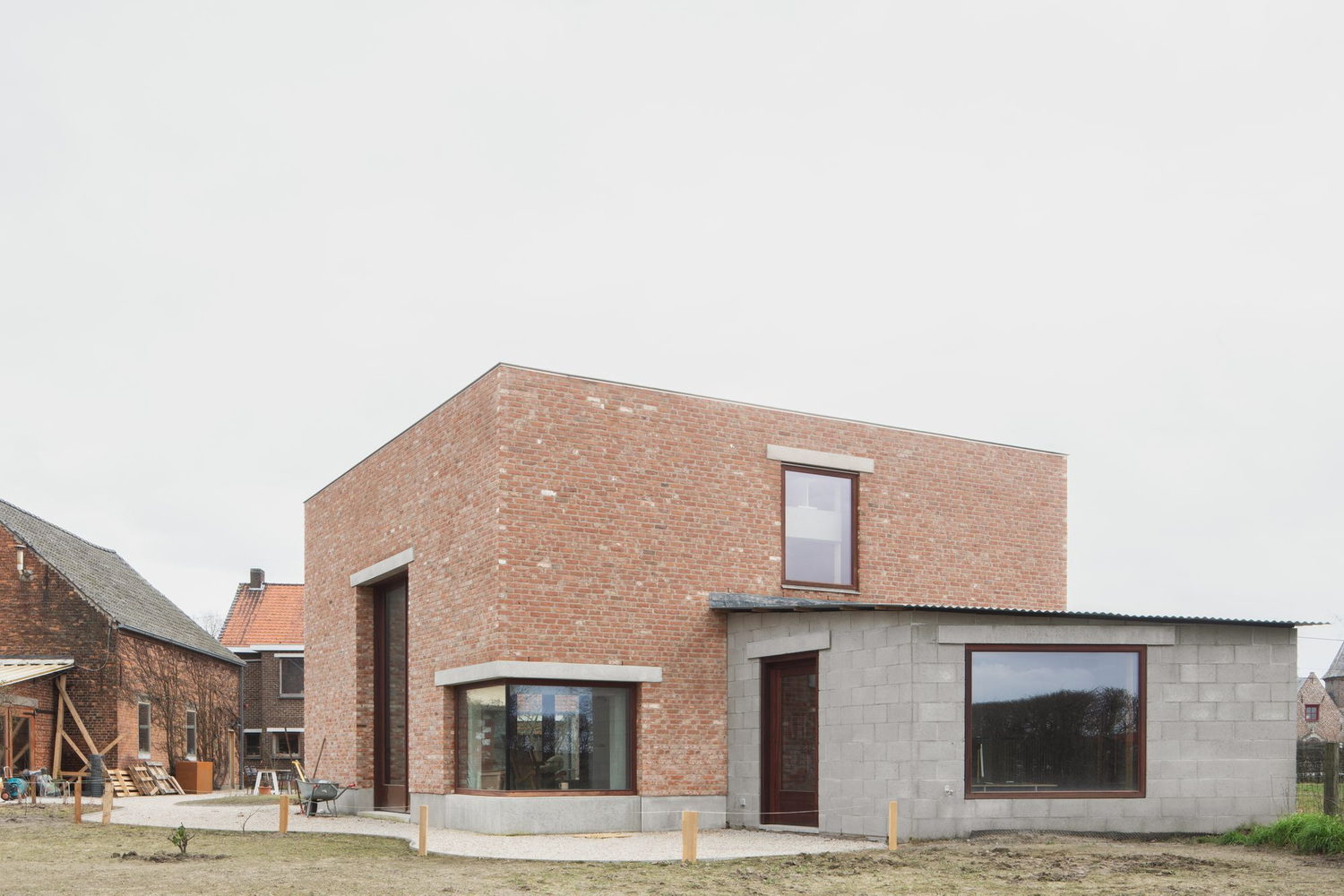 Studio SDS by GRAUX & BAEYENS — The studio's brick volume presents a geometric composition dominated by a horizontal window with deep concrete lintel and sill that frames the winter...