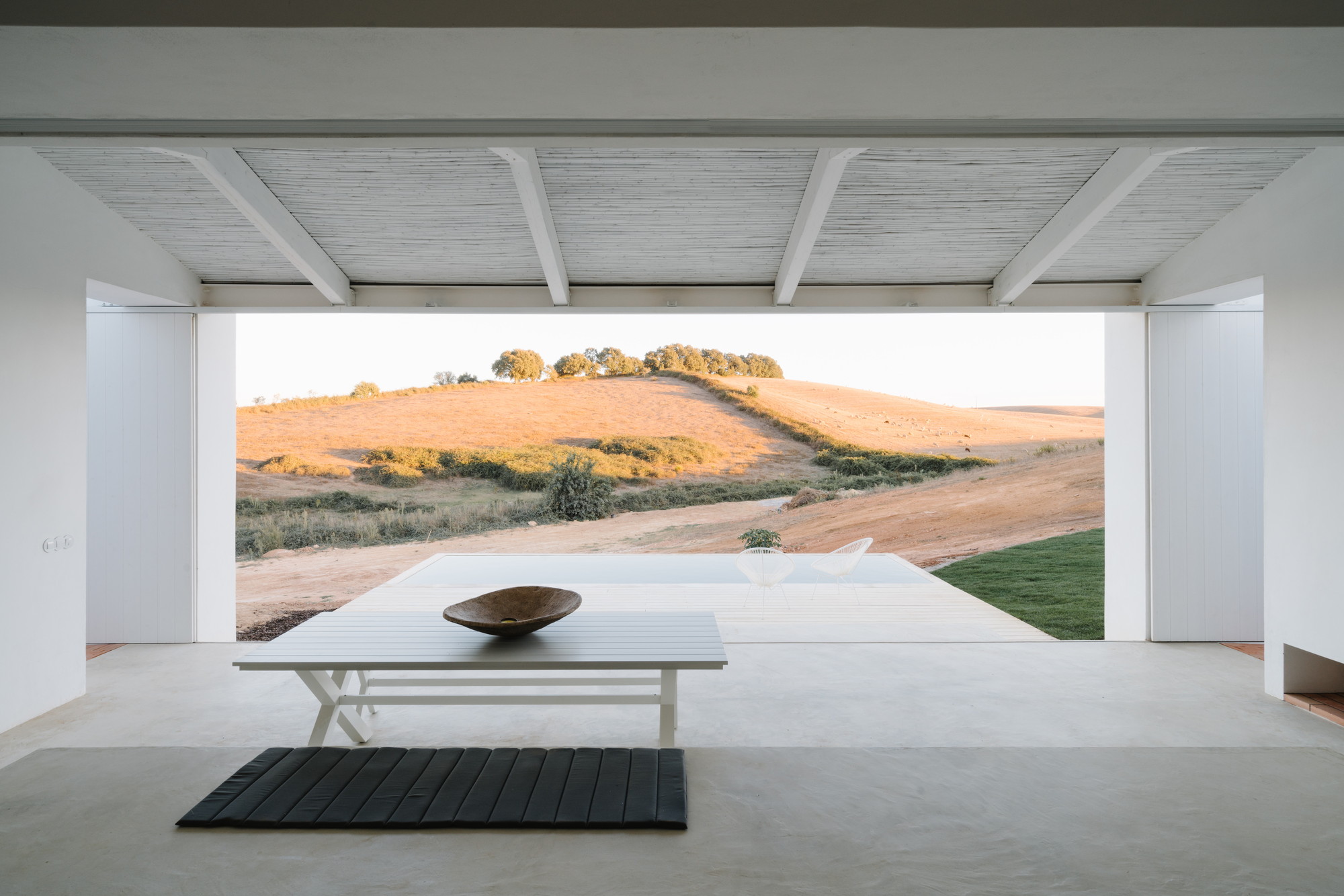 Cercal House by Atelier Data — A minimal interior threshold frames an expansive Alentejo landscape through floor-to-ceiling glazing.