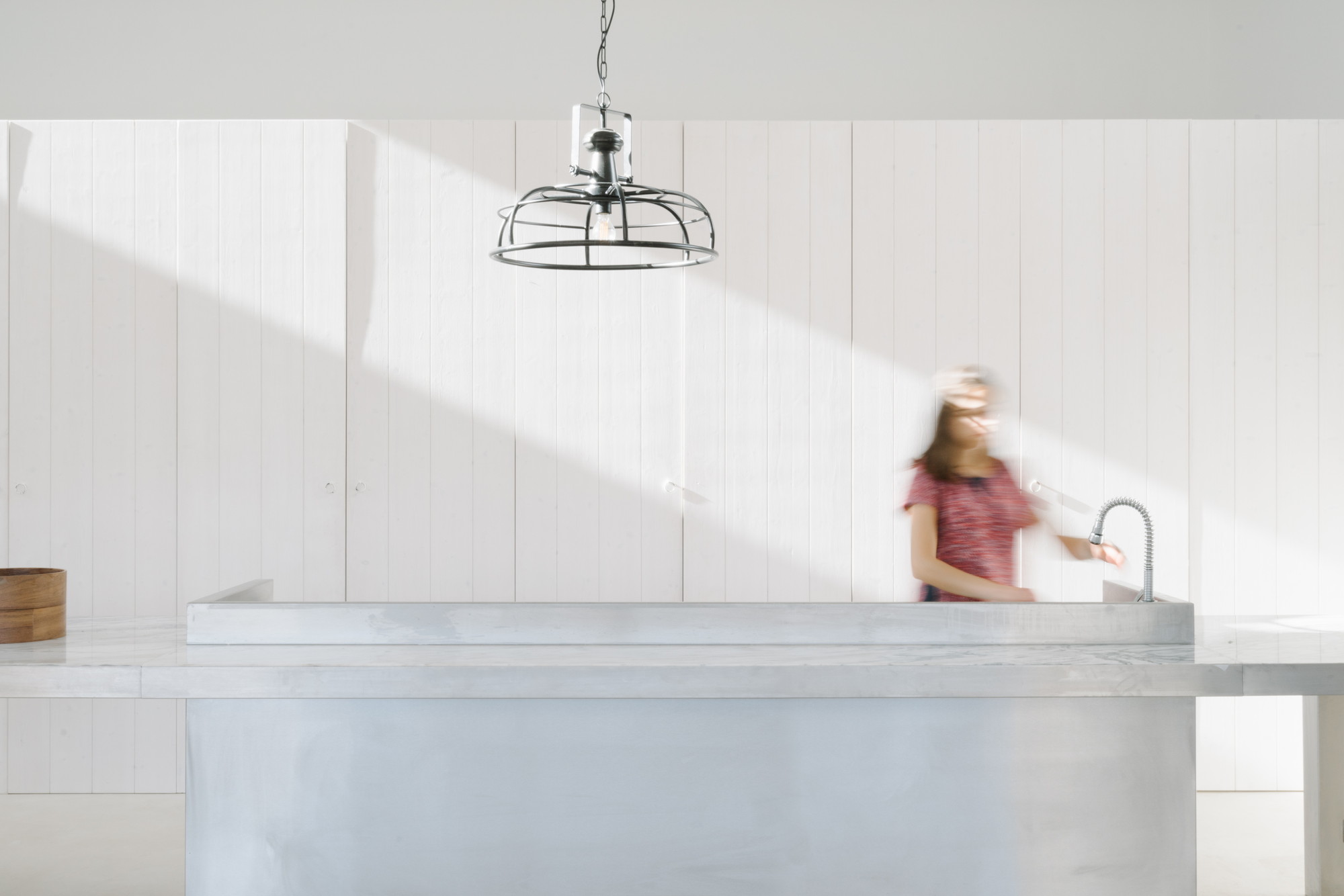 Cercal House by Atelier Data — A kitchen counter in Cercal House features a rendered white wall backdrop with vertical board detailing.