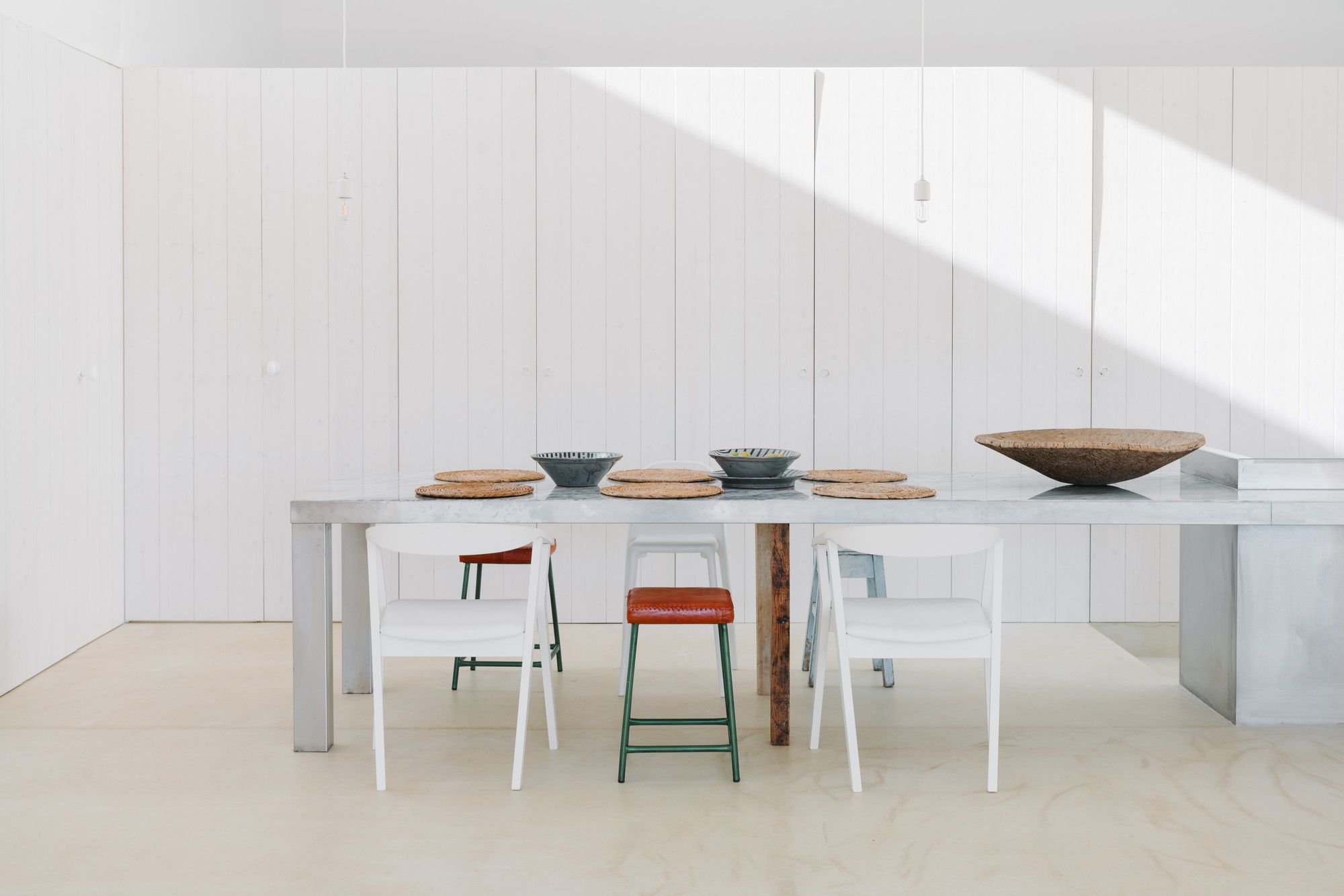 Cercal House by Atelier Data — Interior dining space with rendered white walls and vertical board paneling.