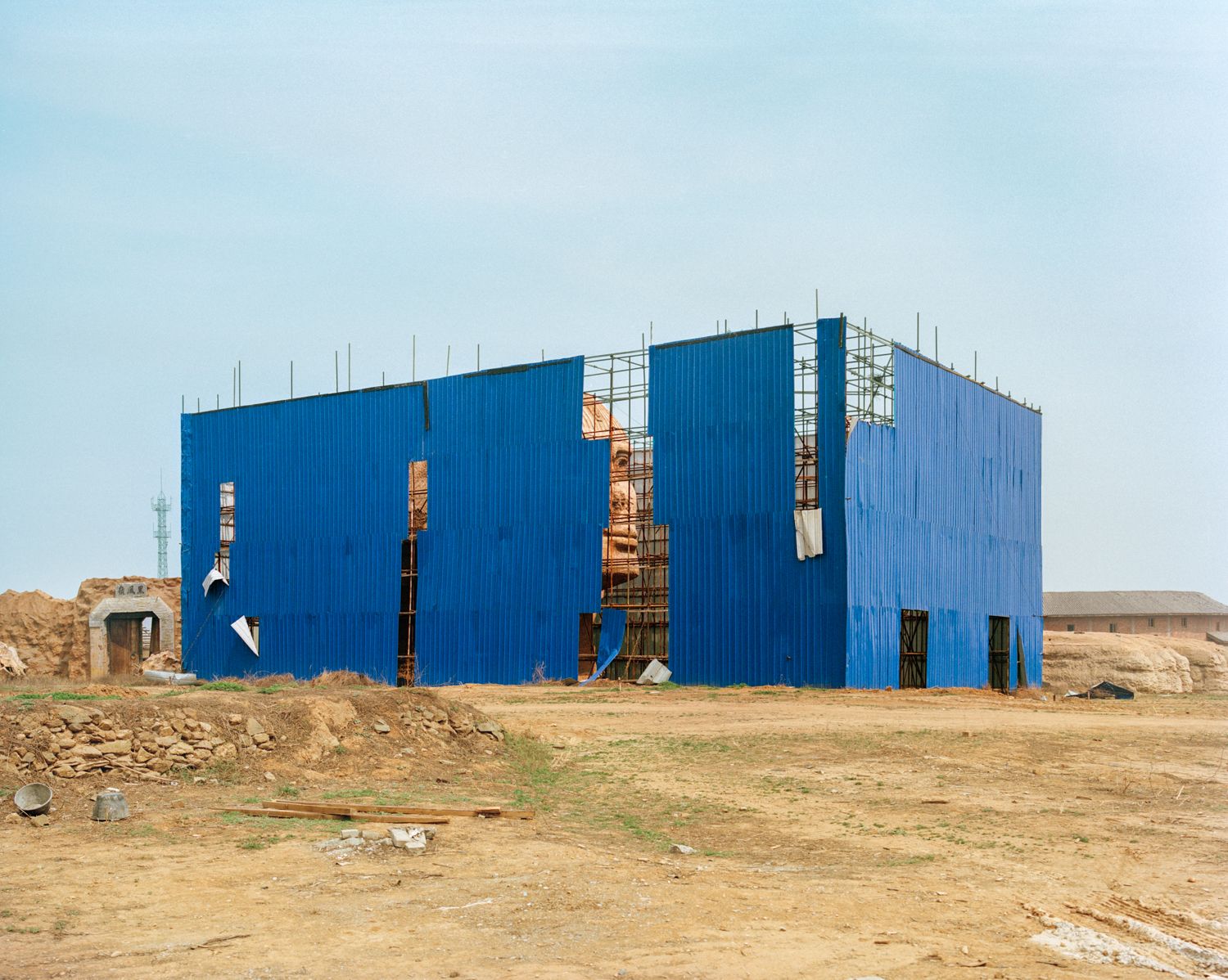 I am just a scenic spot by Pauilne Niks — A large-scale industrial structure clad in corrugated steel panels in cobalt blue dominates the composition, its facade punctuated by rectangular apertures...