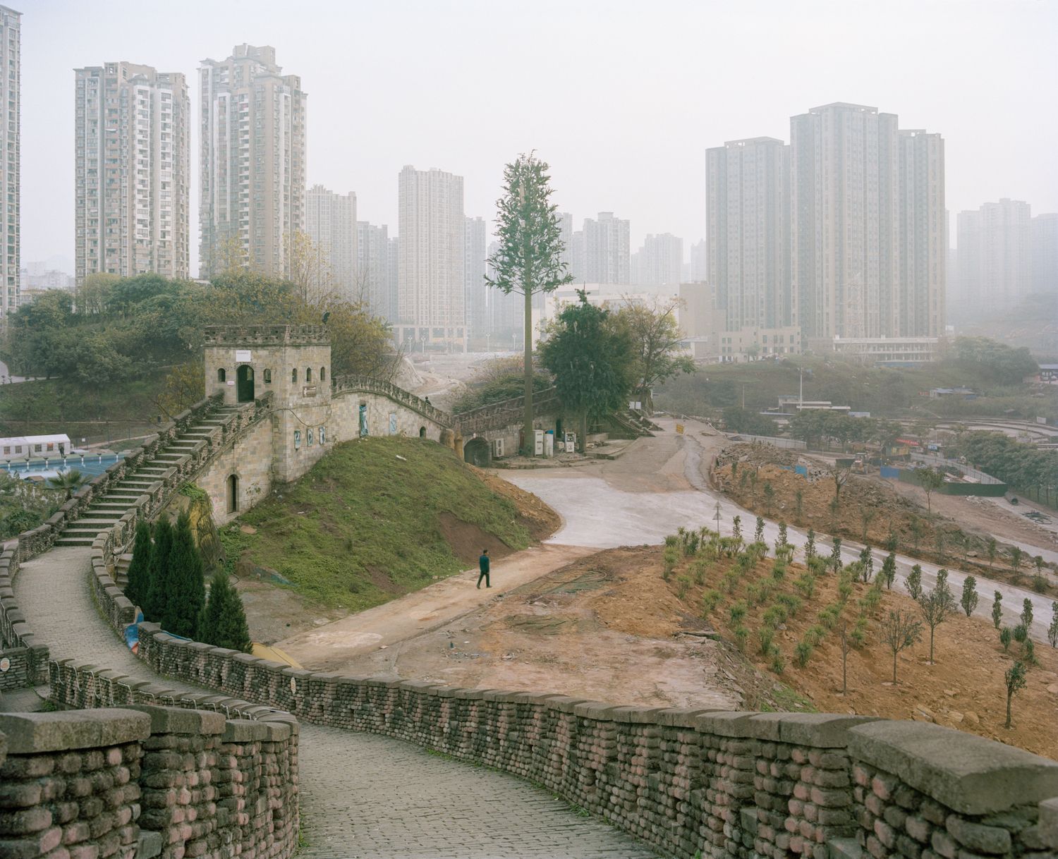 I am just a scenic spot by Pauilne Niks — A reconstructed stone fortification with crenellated walls and stone staircase occupies the foreground of this landscape photograph, its weathered masonry...