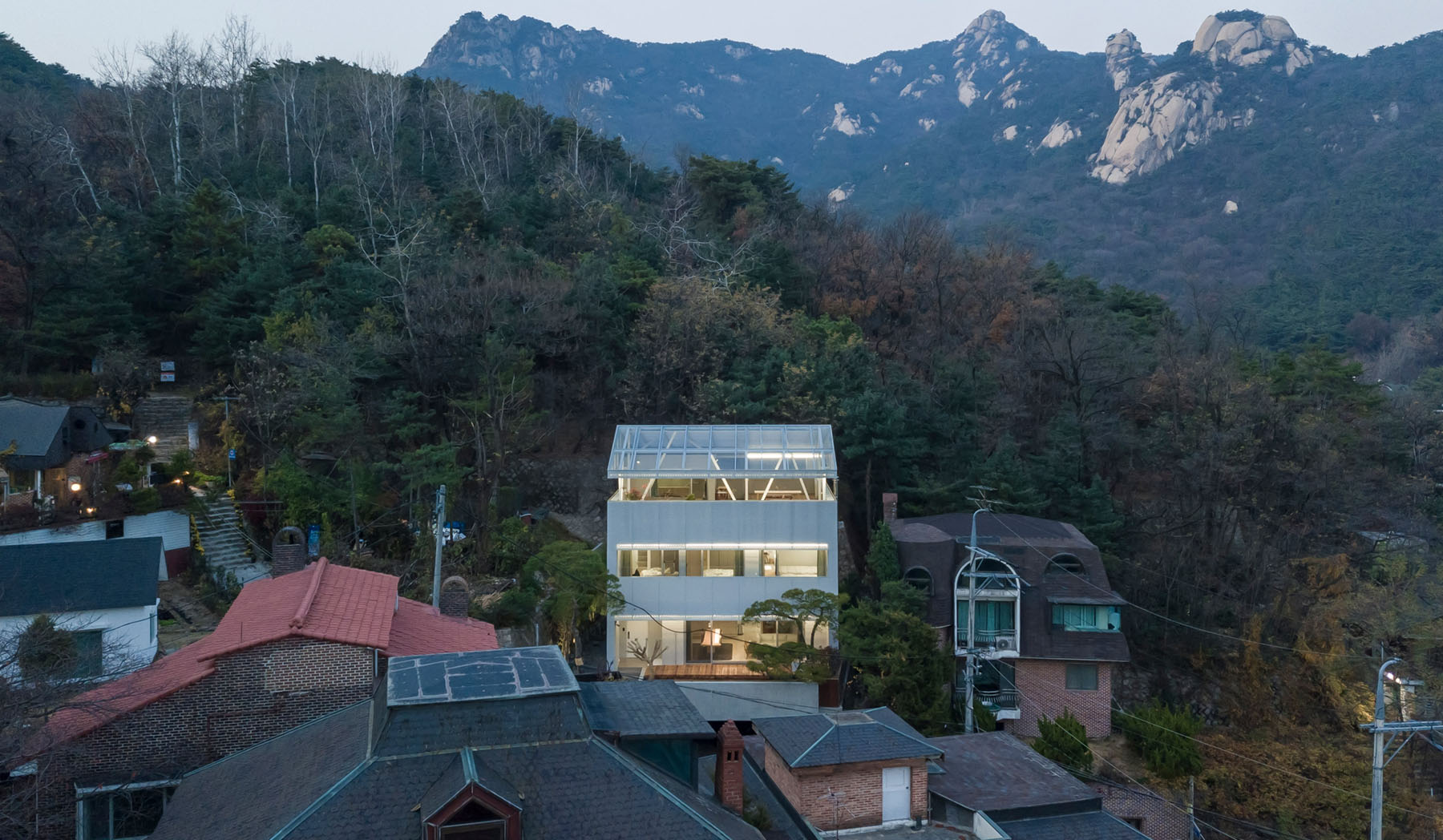 The Shaded Rooftop House by BCHO Architects — Evening photograph of the Shaded Rooftop House captured from an elevated vantage point overlooking the Seoul neighborhood.