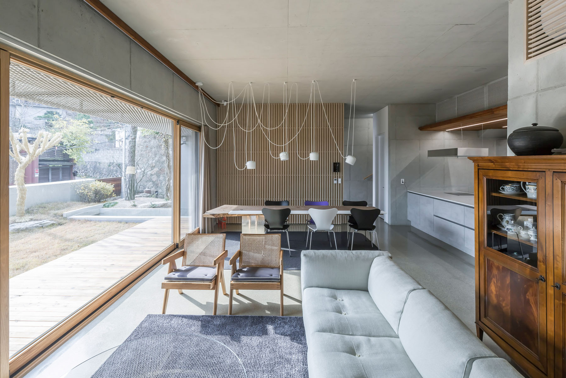 The Shaded Rooftop House by BCHO Architects — The open-plan living and dining area showcases the project's integration of interior and exterior spaces through expansive timber-framed glazing.