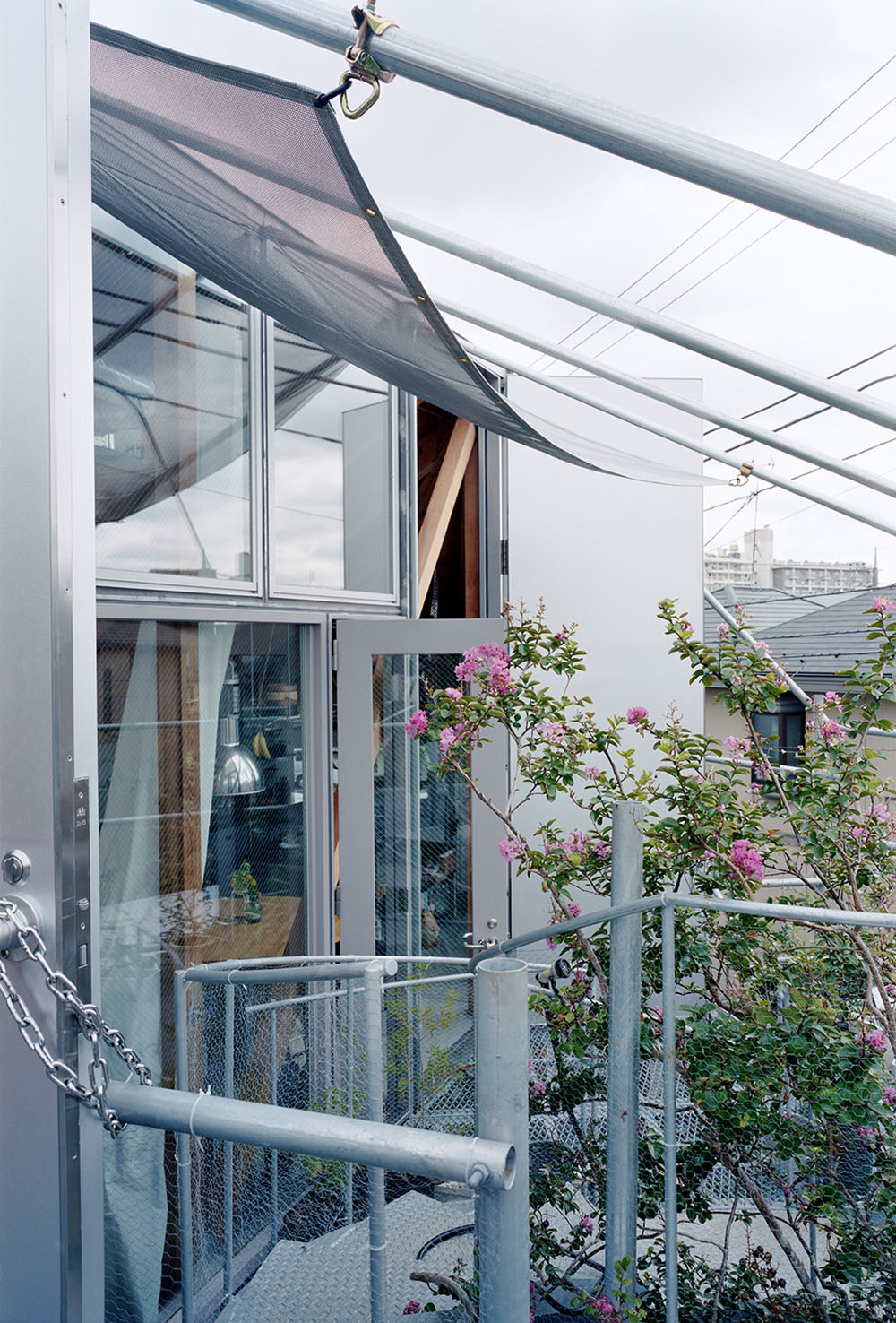 Daita2019 House by Suzuko Yamada Architects — A rooftop terrace framed through multi-layered glazing and steel lattice framework.