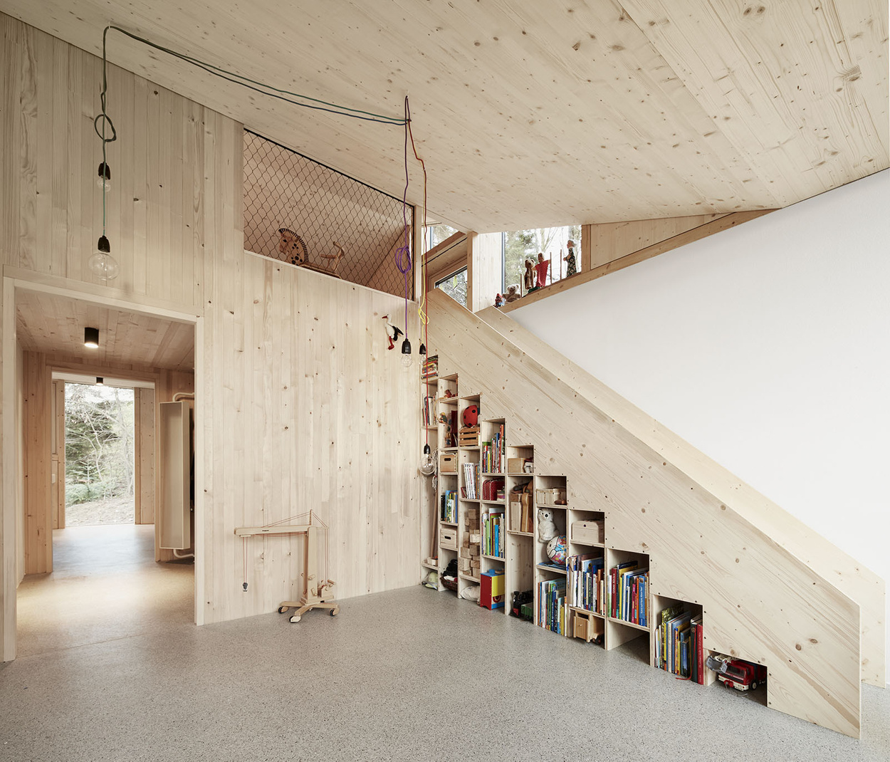 House Hohlen by Jochen Specht — Interior view of the House Hohlen's double-height living space, showcasing the architectural integration of storage and circulation.