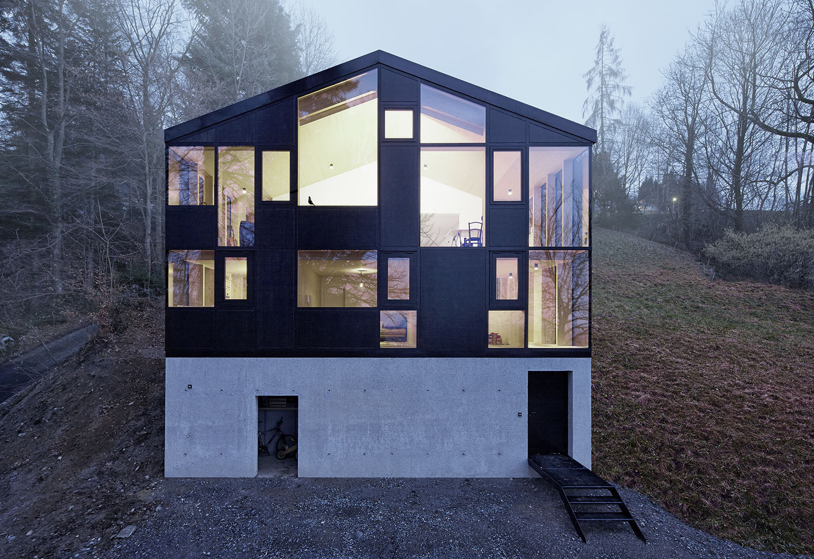 House Hohlen by Jochen Specht — Jochen Specht's House Hohlen presents a two-part volumetric composition: a recessed concrete plinth with utilitarian openings anchors the structure to...