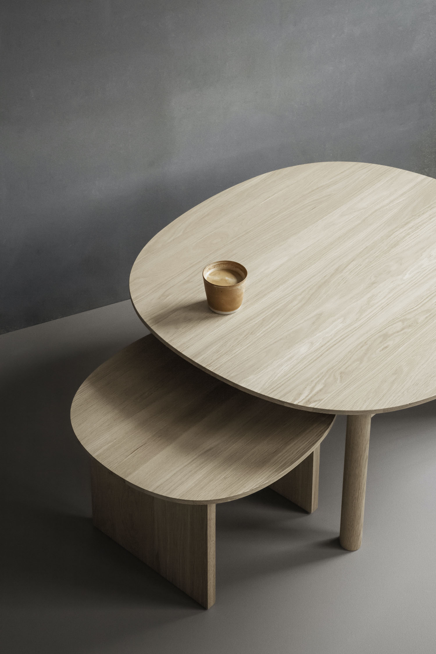 Sling Tables by Industrial Facility — Sling Tables by Industrial Facility presents a nested stacking arrangement of two coffee tables in light oak, demonstrating the super-ellipse form that...