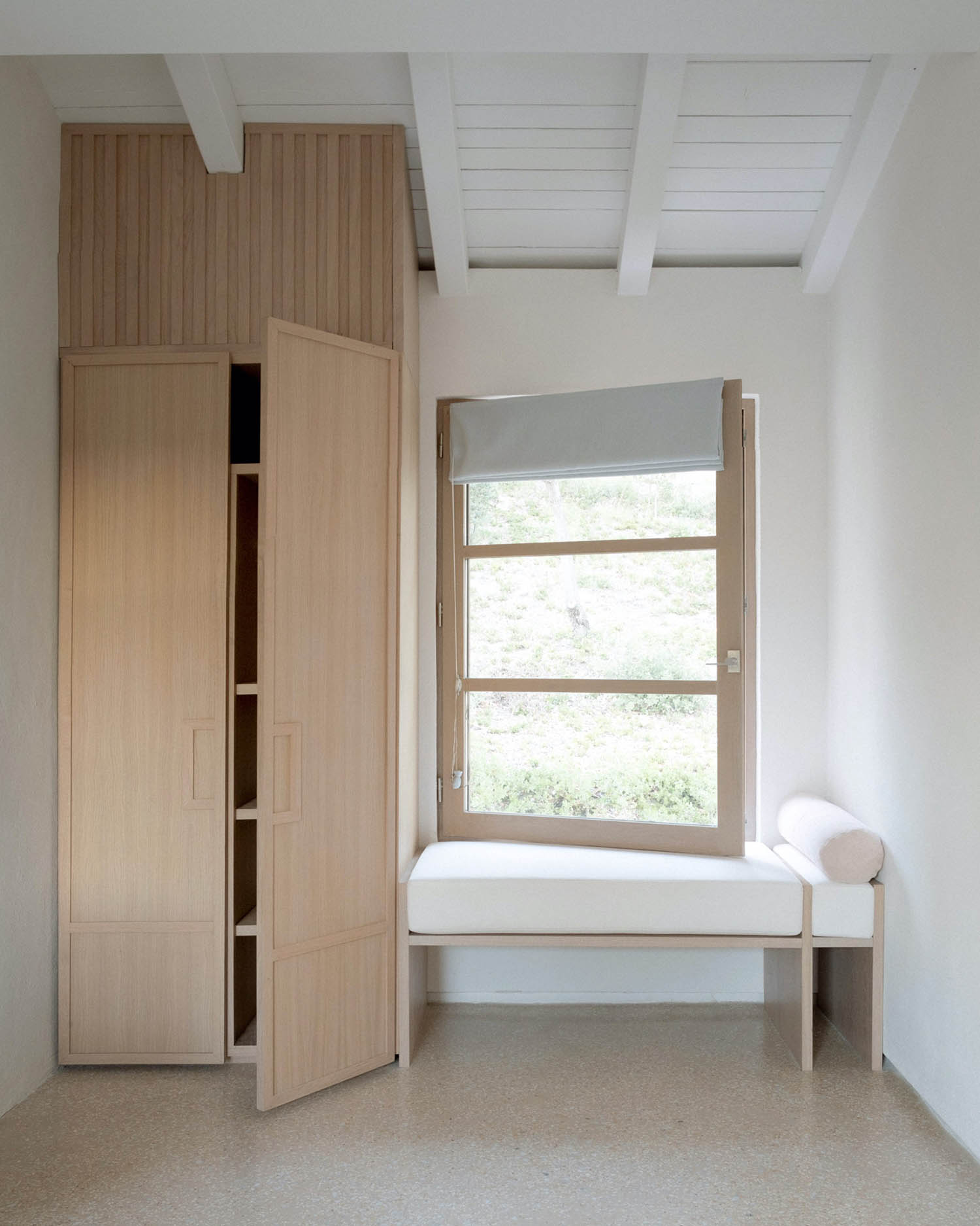 MA House by Studio XM — Interior view of a bedroom featuring a custom timber wardrobe with vertical board paneling and recessed panel doors in light oak, positioned against the...