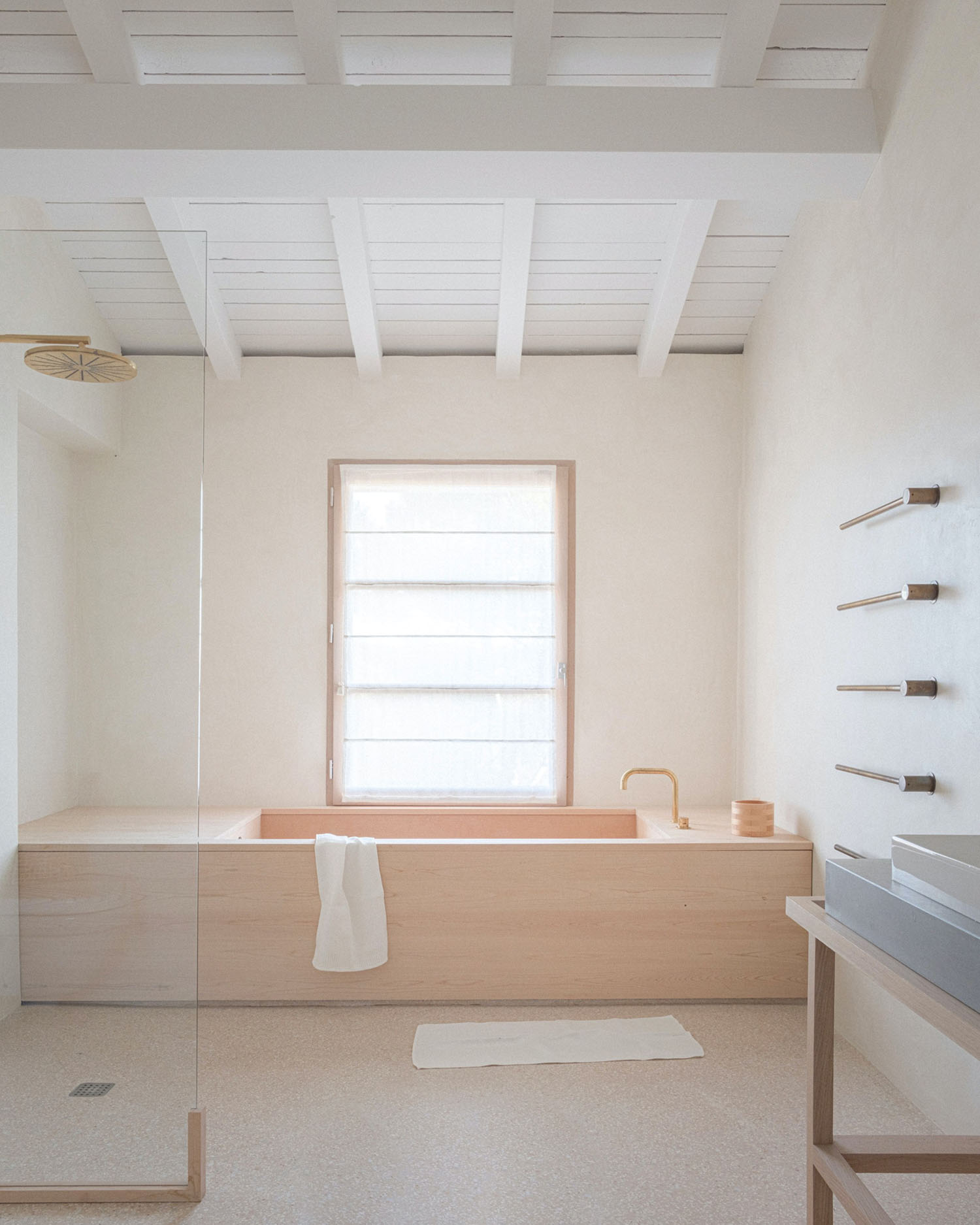 MA House by Studio XM — The bathroom at MA House features a wood-clad bathtub in light timber, positioned beneath a horizontally-banded window with wooden frame that provides...