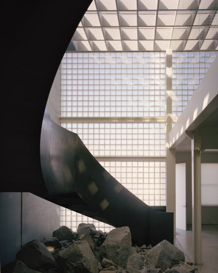 Yoga Studio by Richard Stampton — A curved black steel form descends dramatically into the atrium, its sculptural mass creating sharp contrast against the bright overhead plane.