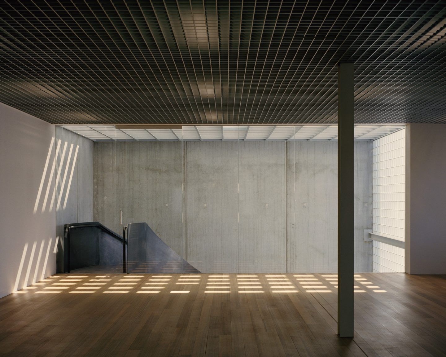 Yoga Studio by Richard Stampton — A gridded translucent ceiling filters overhead light into uniform horizontal bands across the timber floor, creating a measured rhythm of illumination.