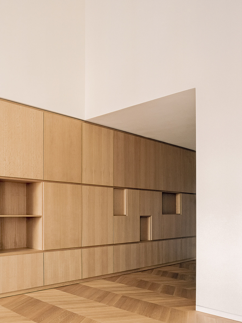 House for a Couple by SET Architects — This interior view showcases a continuous wall of flush-mounted timber cabinetry spanning the full width of the room.