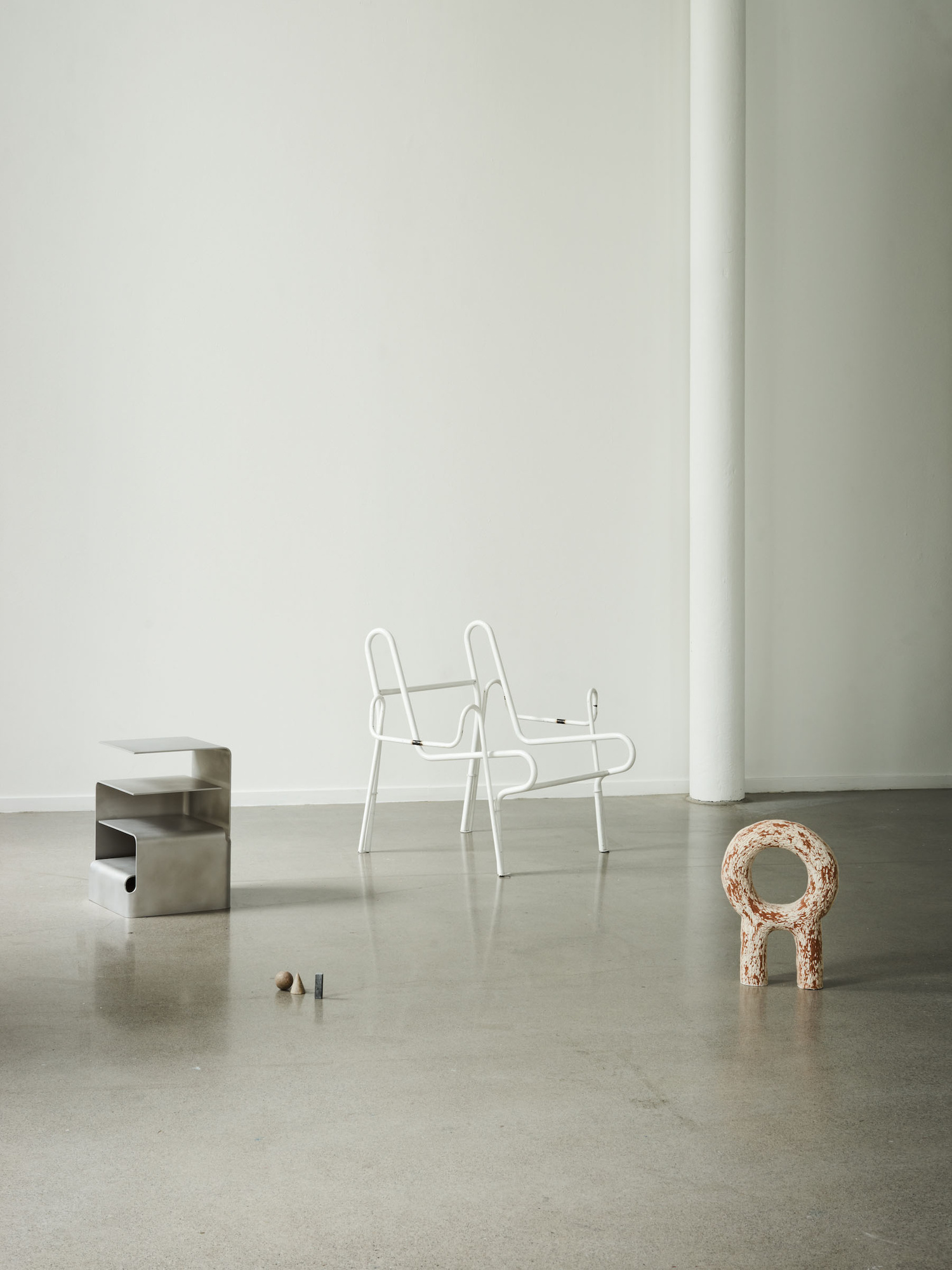 Unika Auction by Bjørn van den Berg and Falke Svatun — Installation view featuring three distinct design objects on polished concrete floor beneath white column.