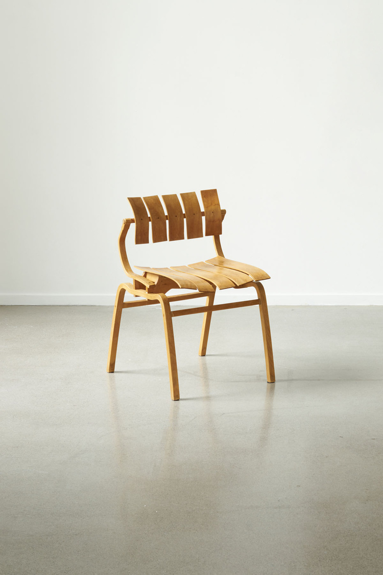 Unika Auction by Bjørn van den Berg and Falke Svatun — A wooden chair with curved bentwood frame and slatted backrest, photographed in profile against a neutral white wall and polished concrete floor.