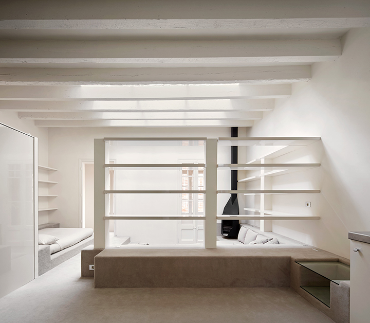Barcelona Apartment Renovation by Arquitectura-G — The renovated Barcelona apartment employs stepped floor platforms in warm grey to articulate spatial zones within the 55-square-metre open plan.
