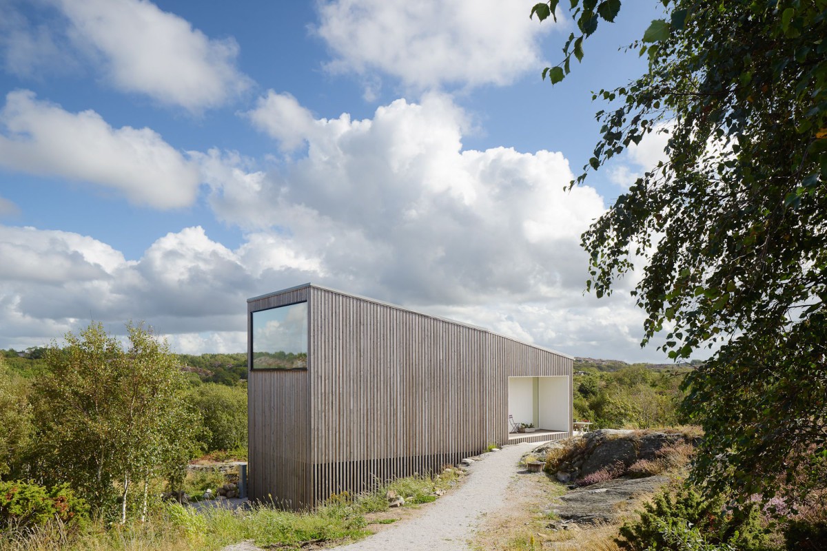 Kyrkesund Weekend House by Mattias Gunneflo — Kyrkesund Weekend House presents a corrugated metal structure with weathered patina set within rocky Scandinavian terrain.