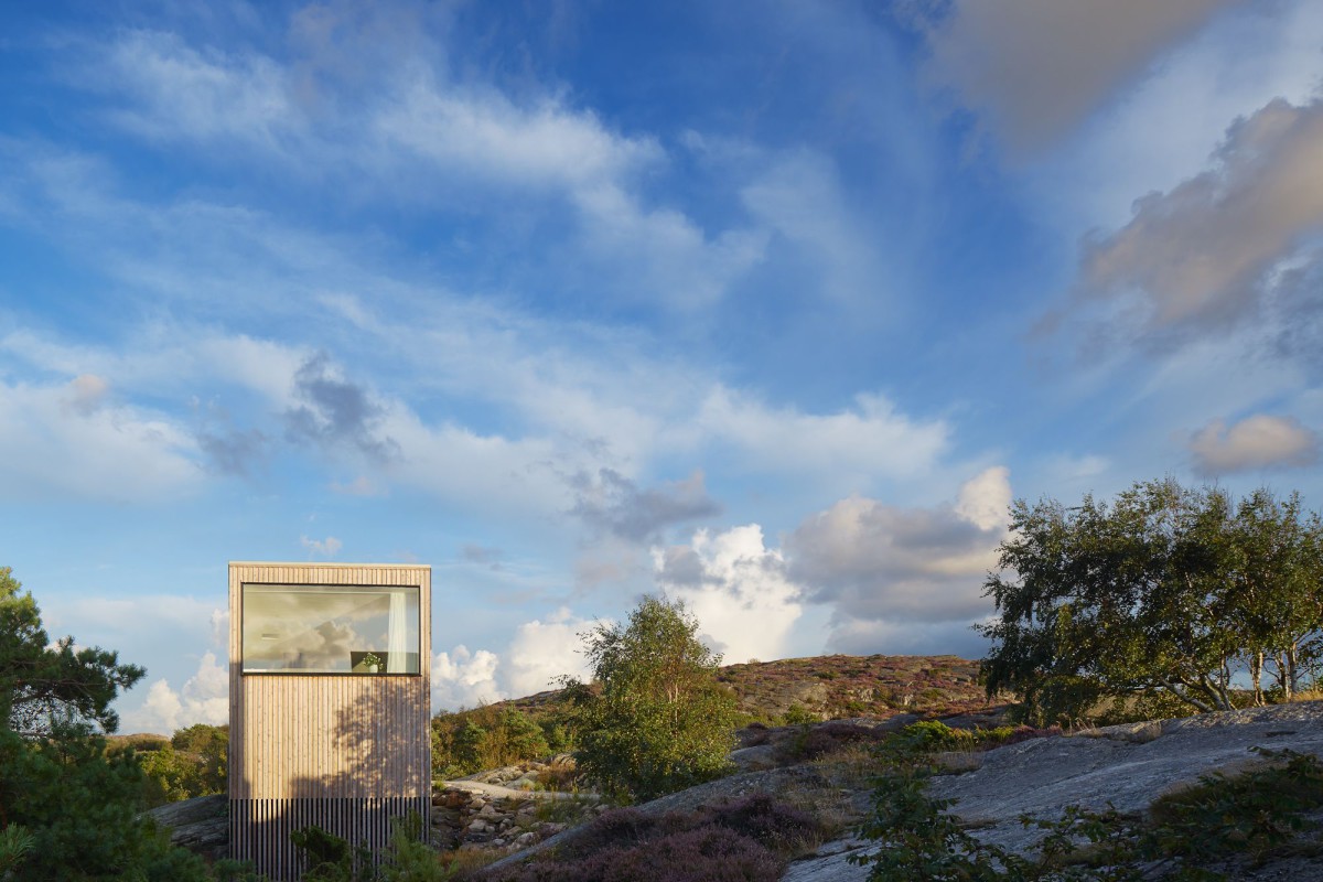 Kyrkesund Weekend House by Mattias Gunneflo — A corrugated metal-clad weekend house sits elevated on slender supports within Sweden's rocky terrain.