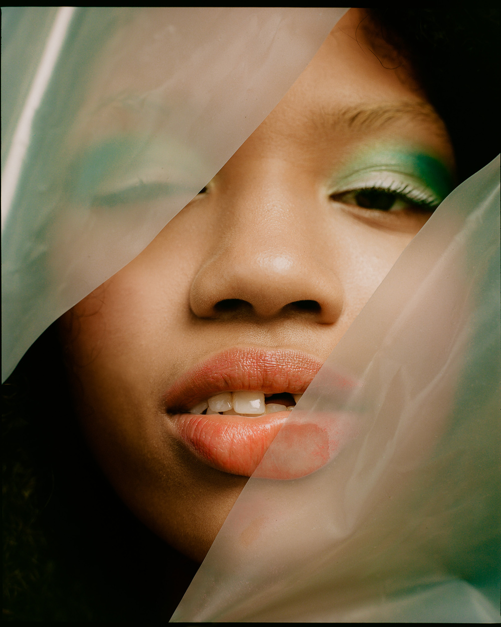 Selected works by Leeor Wild — A close-up portrait study featuring a face partially obscured by translucent green fabric or material.