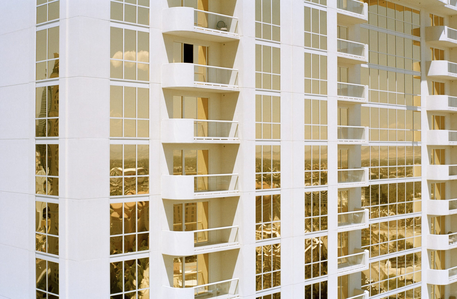 Selected works by Leeor Wild — A residential facade composed of gridded window systems and white vertical mullions, punctuated by recessed concrete balconies that project outward in a...