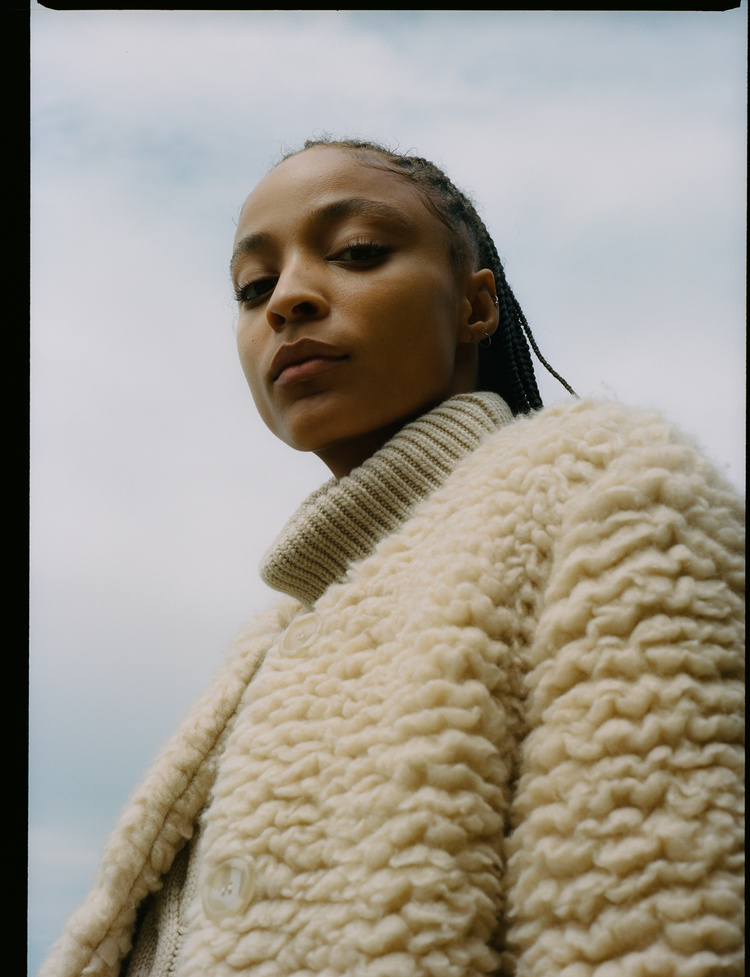 Selected works by Leeor Wild — Close-up portrait shot against overcast sky, subject turned slightly away from camera with downward gaze.