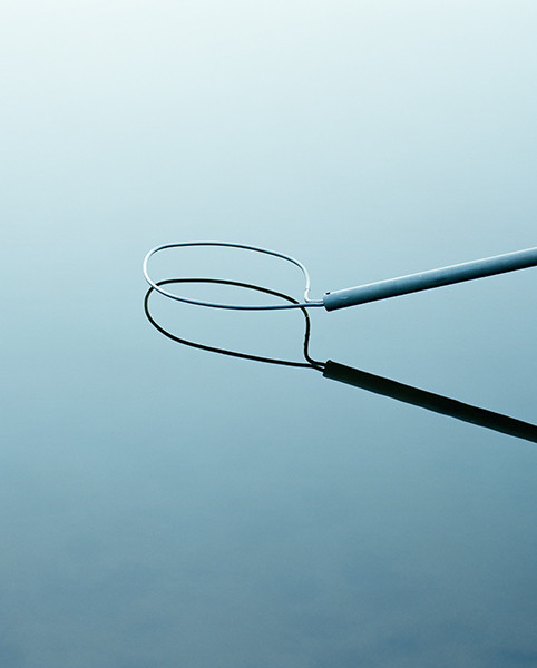 The Circle and the Line by Erik Östensson — Two lengths of cable—one pale blue, one black—extend from the right edge against a gradient blue ground.