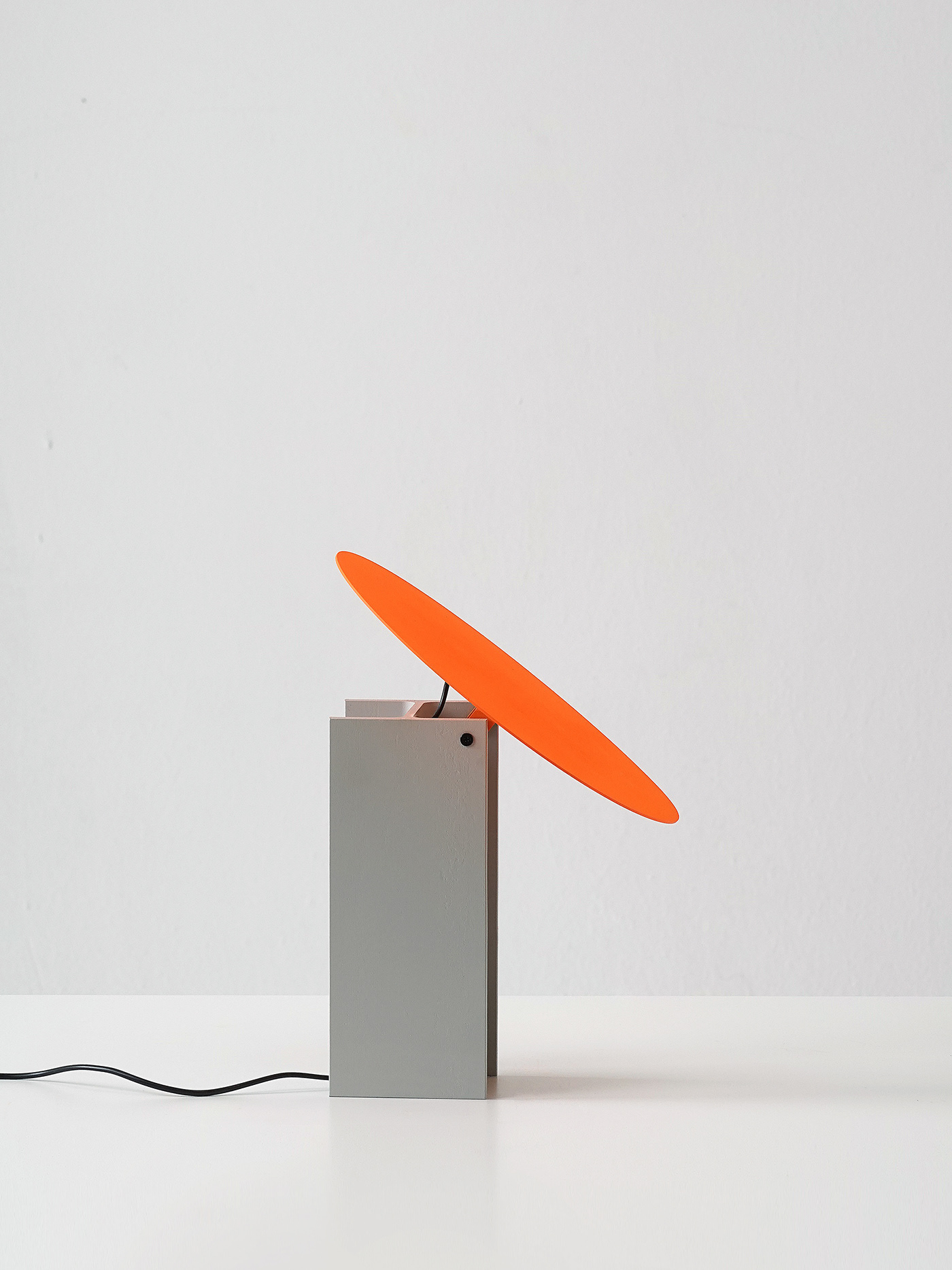 H-beam Lamp Series by SF-SO — The H-beam Lamp Series presents a sculptural table light with a rotating cylindrical lampshade in vibrant orange, mounted on a rectangular concrete base...