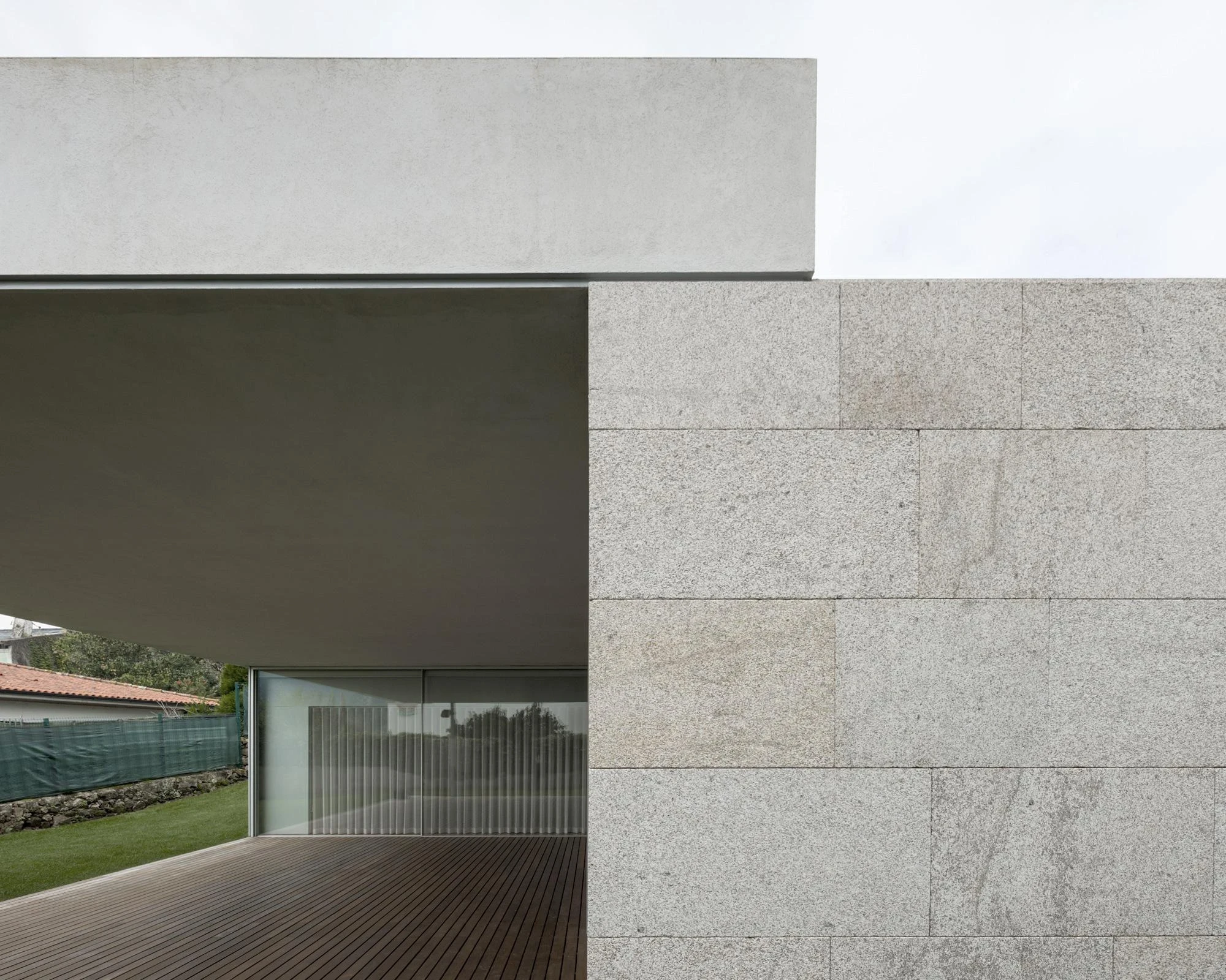 Santo Tirso House by Nuno Brandão Costa, Portugal 2014, single-storey house on triangular hillside plot, silvered glass garage volume, L-shaped plan