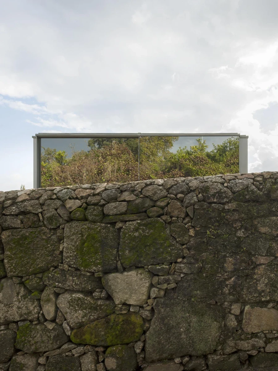 Santo Tirso House by Nuno Brandão Costa, Portugal 2014, single-storey house on triangular hillside plot, silvered glass garage volume, L-shaped plan