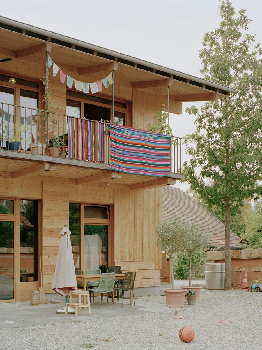 House in Deitingen by studio ou — A two-story timber-clad residential building in Deitingen's village core, photographed from the gravel courtyard.