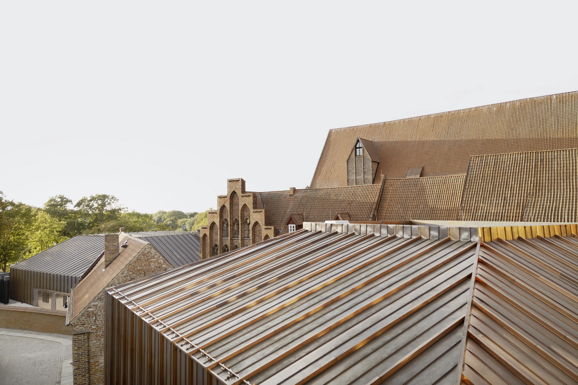 Renovation and Extension of MEERESMUSEUM by Reichel Schlaier Architekten — Corrugated metal roofing dominates the foreground, its galvanized surface weathered with rust-colored patina streaking the horizontal ribs.