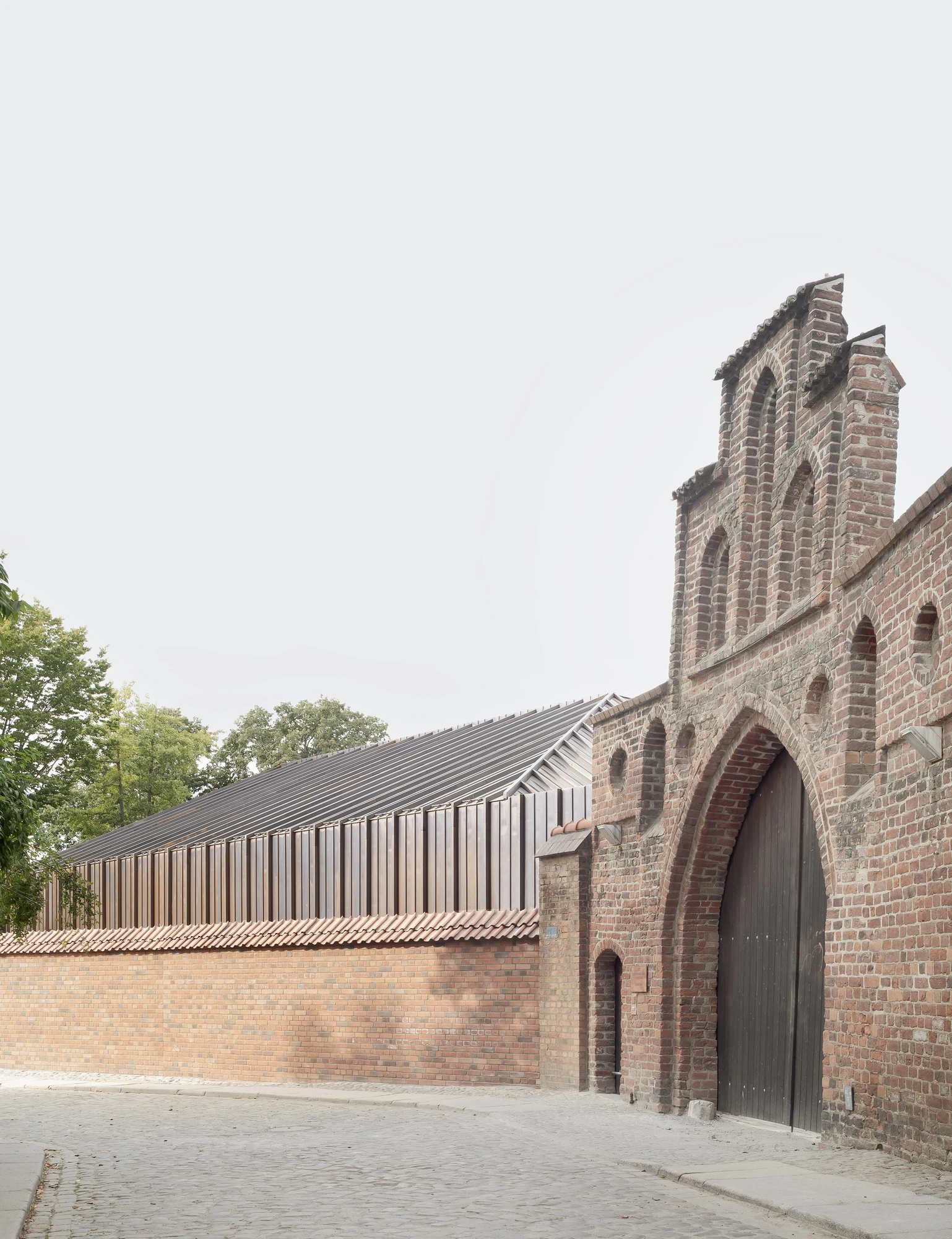 Renovation and Extension of MEERESMUSEUM by Reichel Schlaier Architekten — The monastery's brick façade meets a contemporary pitched-roof extension clad in standing-seam metal paneling.