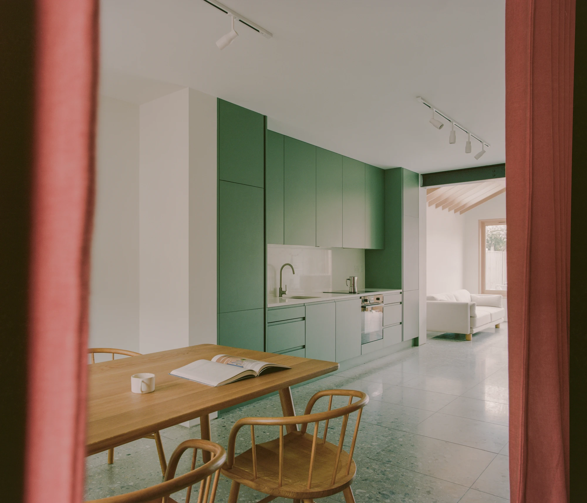 Walthamstow House by PSL — Ground floor kitchen and dining space featuring a green cabinetry wall that extends across the rear of the open plan.