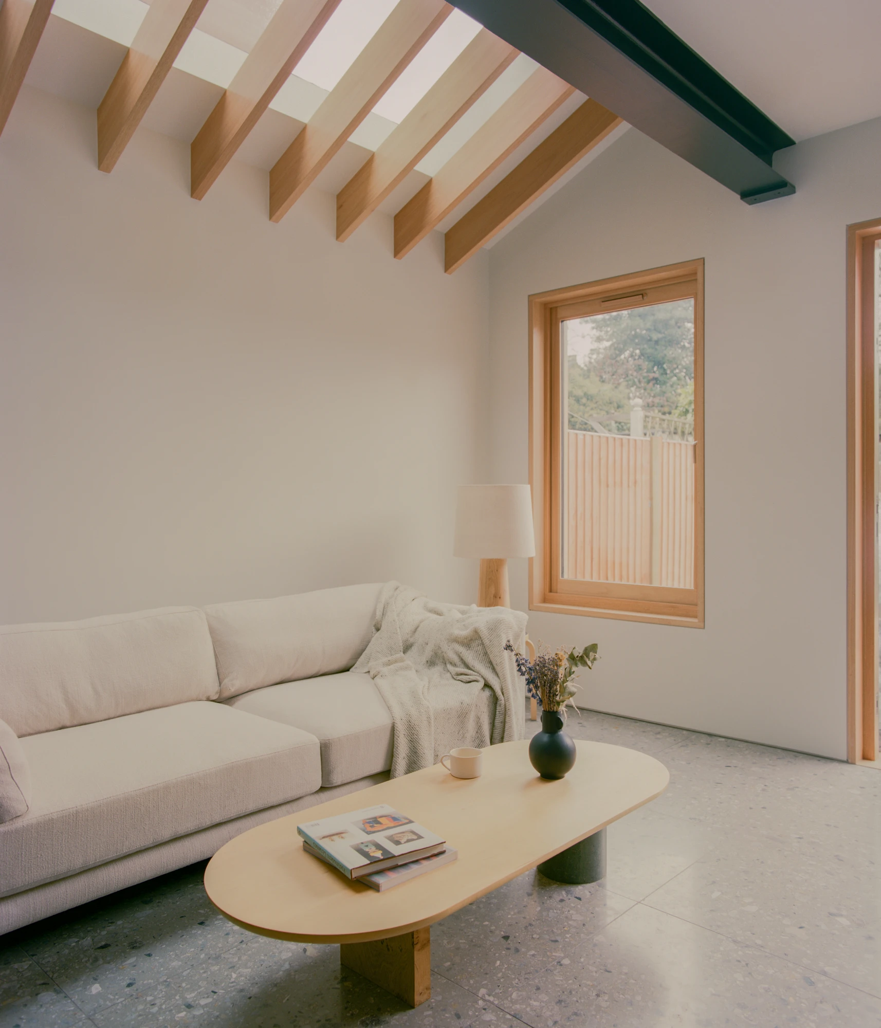 Walthamstow House by PSL — Ground floor living space with exposed timber ceiling joists spanning the width of the room, painted white with natural wood undersides.