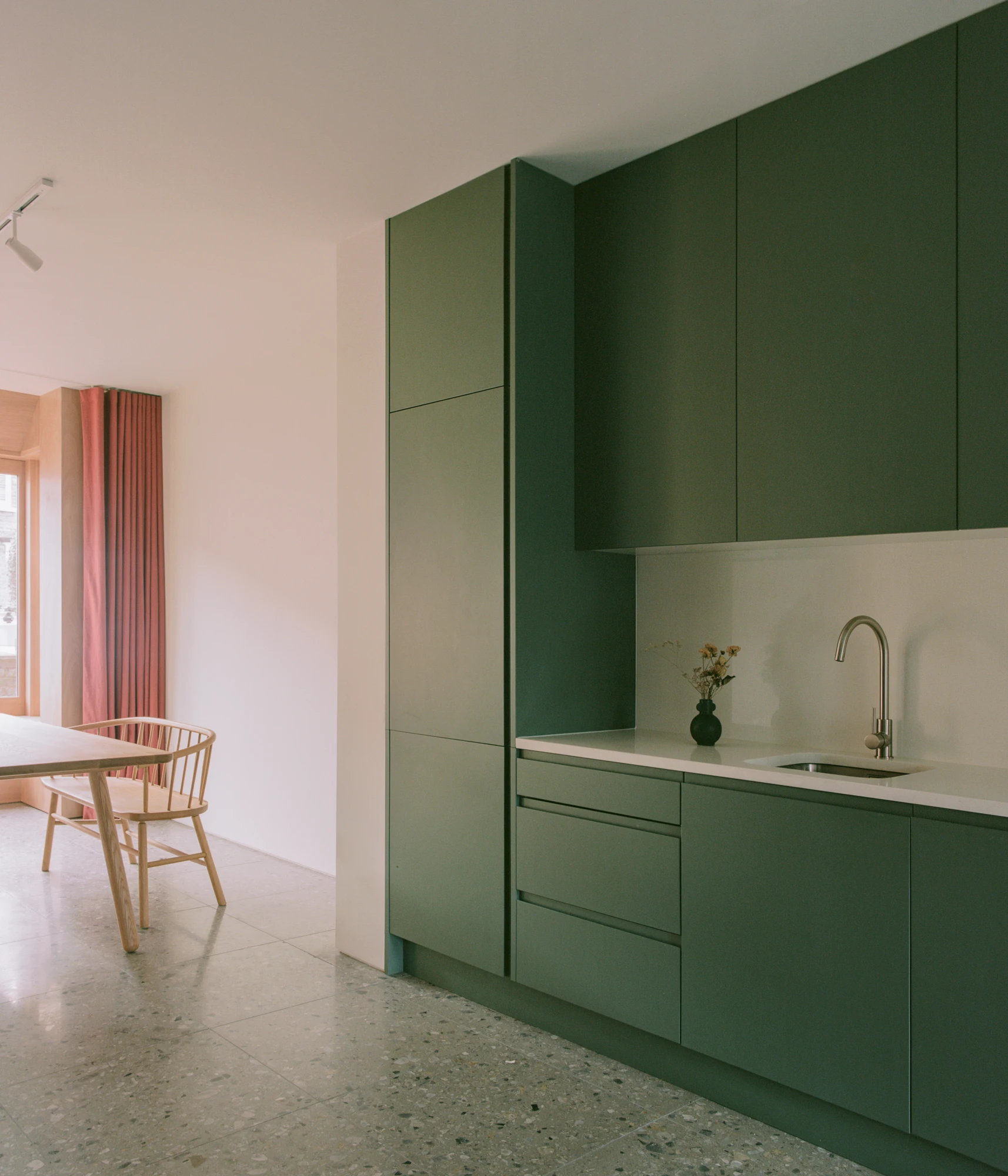 Walthamstow House by PSL — Ground-floor kitchen intervention in deep sage cabinetry creates a strong chromatic anchor within the open-plan space.