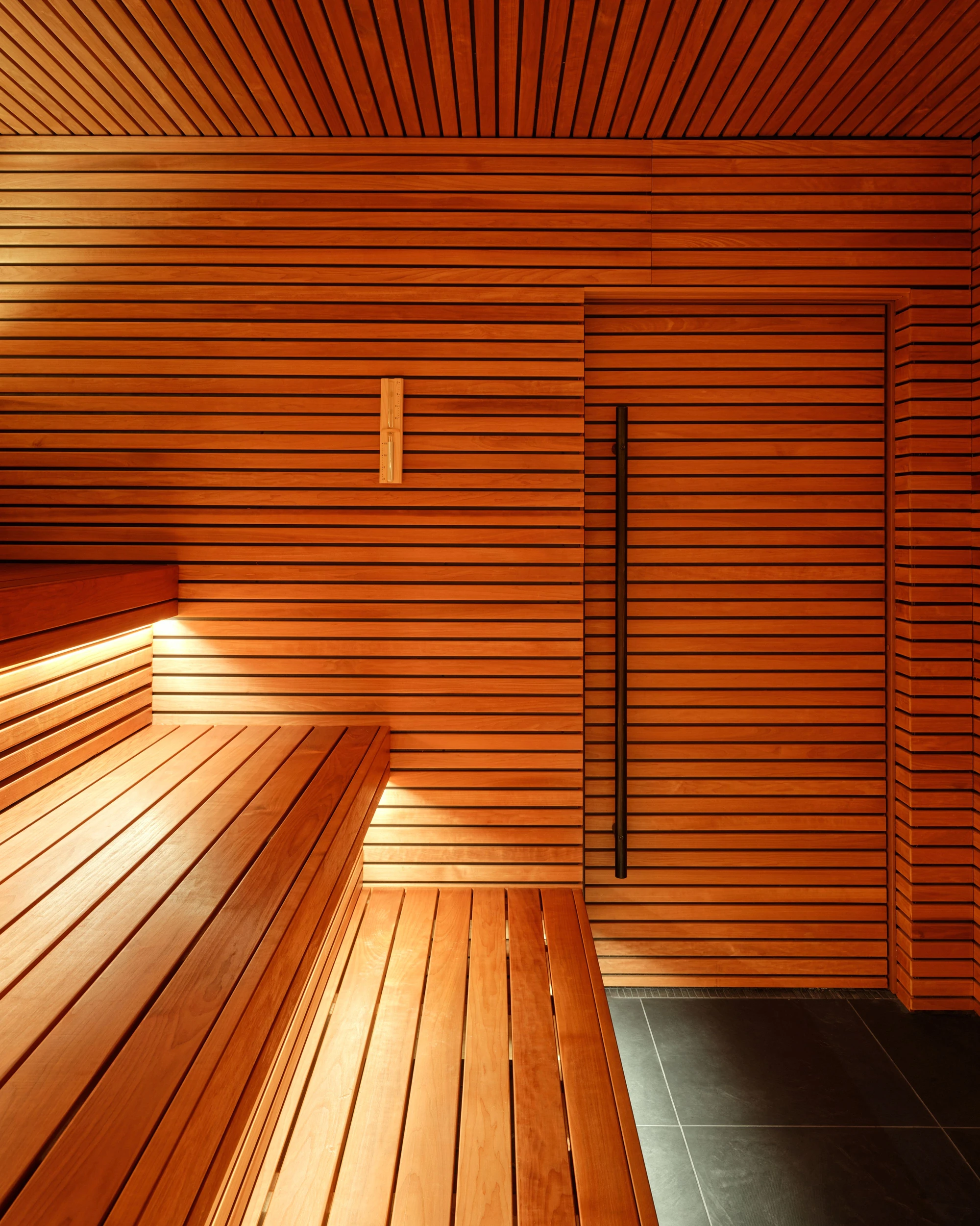 Sant Roch Sauna by Futurstudio — The sauna interior reveals Futurstudio's material strategy through layered timber cladding that spans floor, walls, and ceiling in continuous horizontal planks.