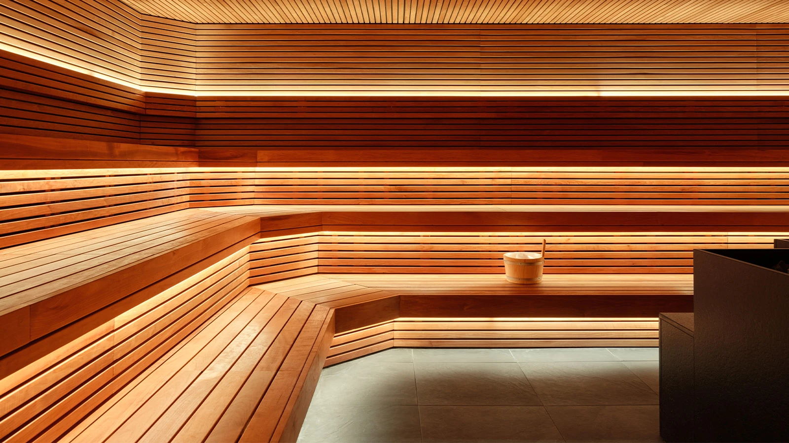 Sant Roch Sauna by Futurstudio — Interior view of Sant Roch's sauna chamber, showing the stepped bench seating arrangement constructed from continuous horizontal timber slats.