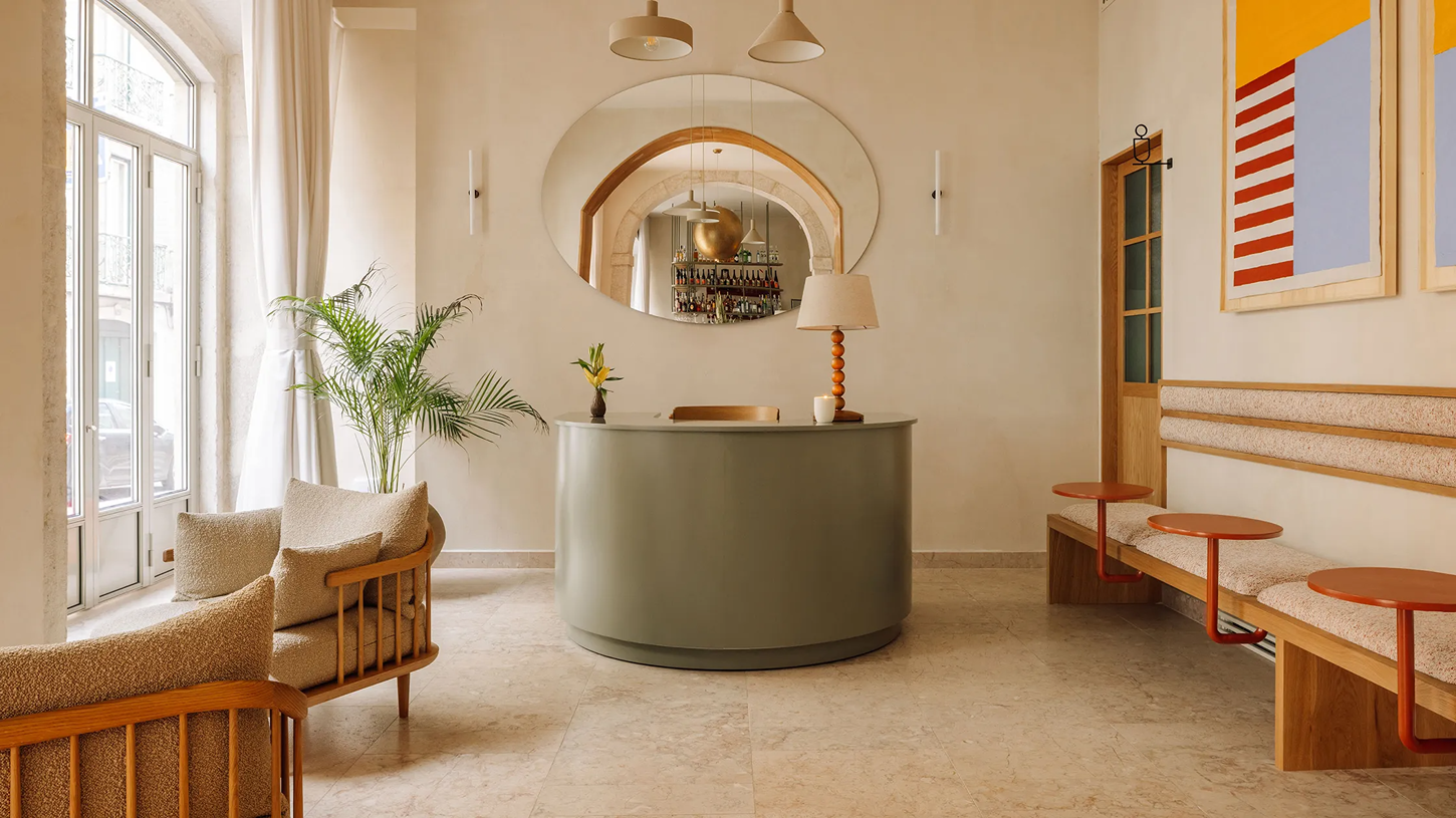 The Verse by João Luís Carrilho da Graça + Studio Astolfi — The reception lobby presents a geometric composition centered on a monolithic sage-green cylindrical desk.