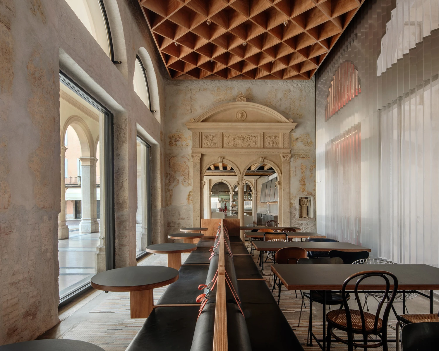 Caffè Nazionale by AMAA — A linear dining passage articulates the restored 19th-century palazzo, where classical plasterwork with relief panels and paired arched openings frames...