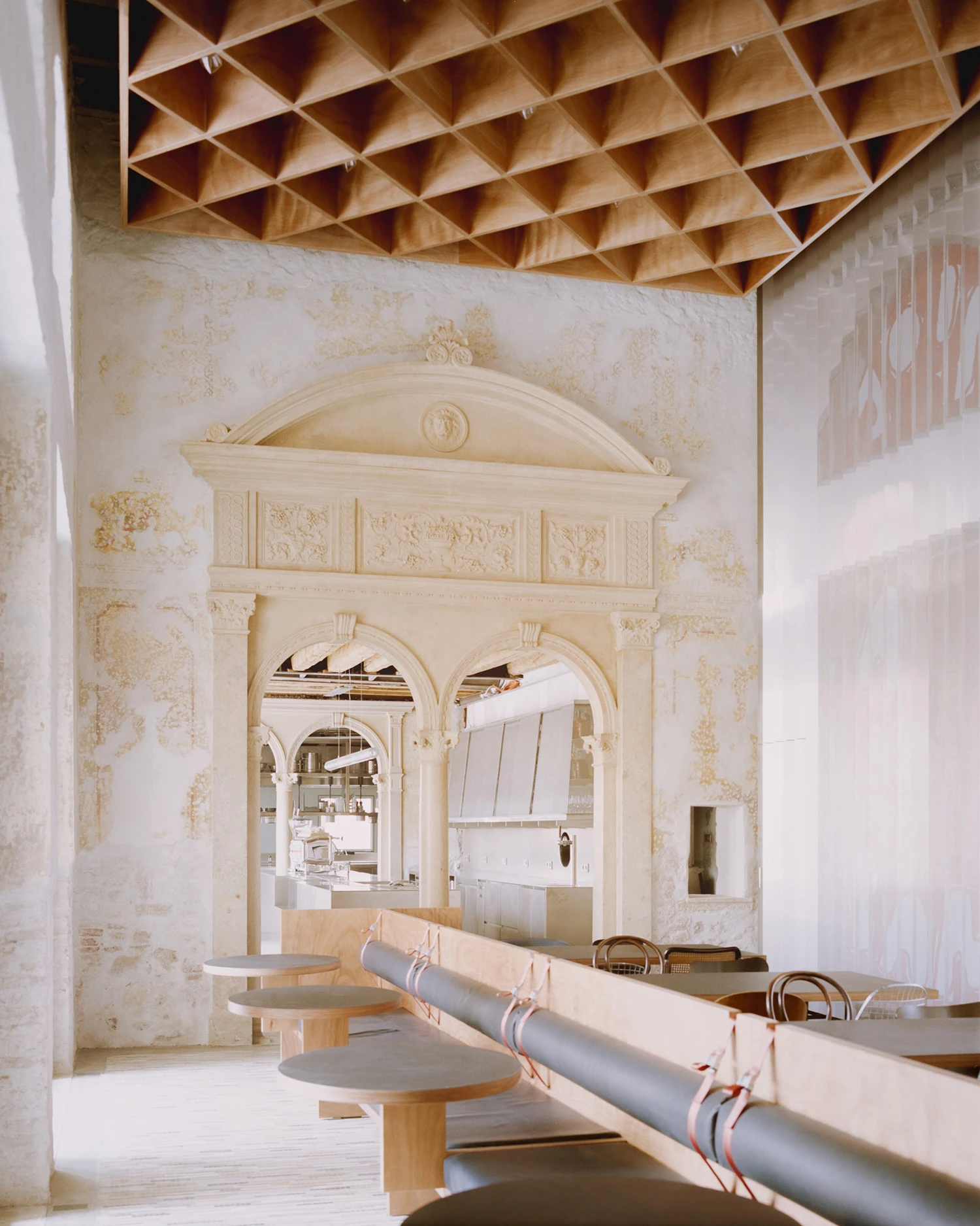 Caffè Nazionale by AMAA — A passage through the restored palazzo reveals layered historical traces on cream-render walls marked by visible staining and weathering.