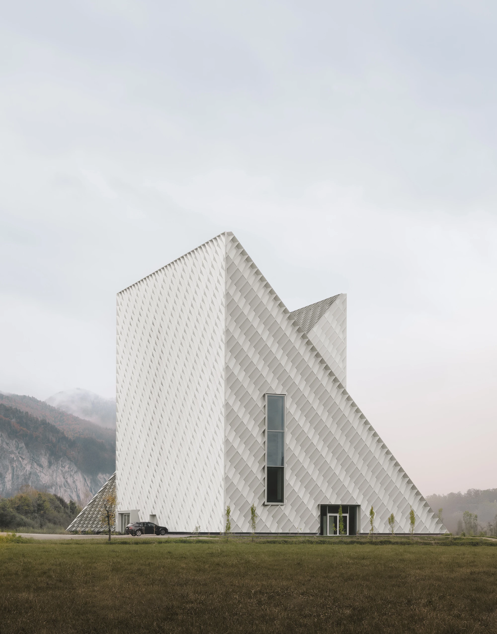Dynafit Headquarters by Barozzi Veiga — Twin pyramidal volumes meet at a sharp apex, their white facades articulated with a continuous diagonal quilted pattern that emphasizes geometric purity.