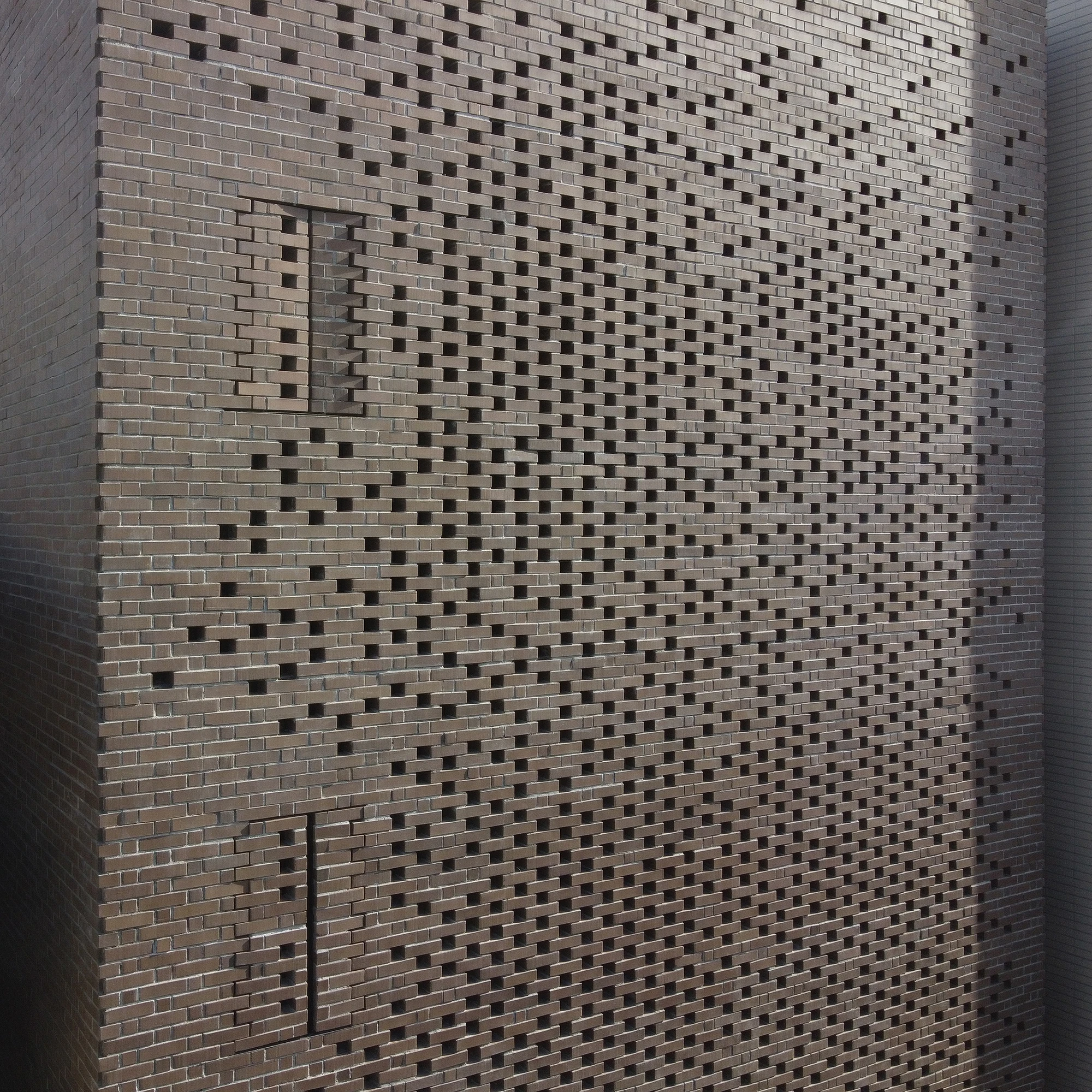 The Veil House by Paperfarm Inc — Close-up detail of the Veil House facade reveals the perforated clay-brick system at maximum density.
