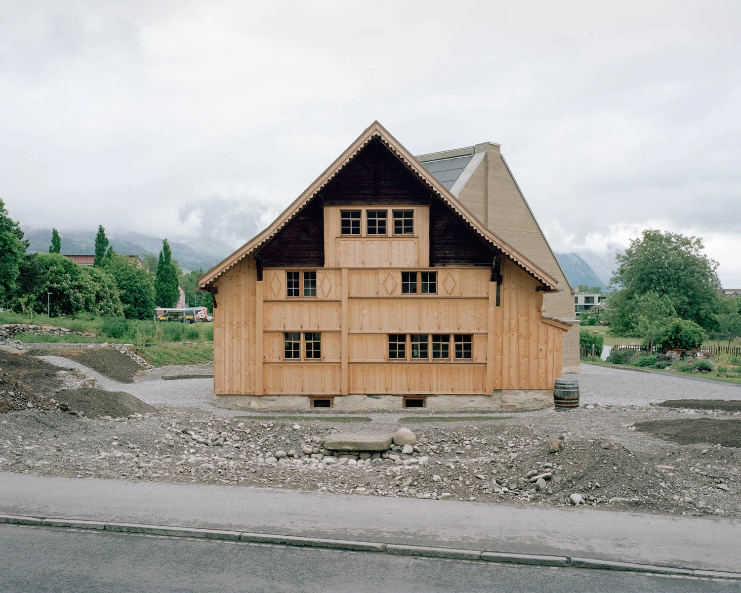 The Gässli5 by allen + crippa architektur — The Gässli5 presents a timber-framed facade clad in light wood planking, its gabled form asserting a distinctive silhouette against the overcast Alpine...